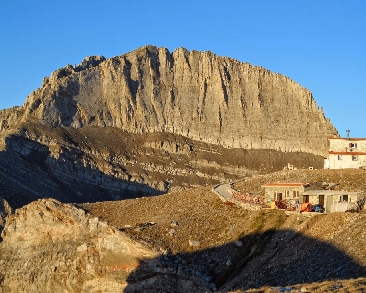 Kakalos Mountain Hut on Mount Olympus, Greece, with Stefani Peak, known as the Throne of Zeus, in the background.