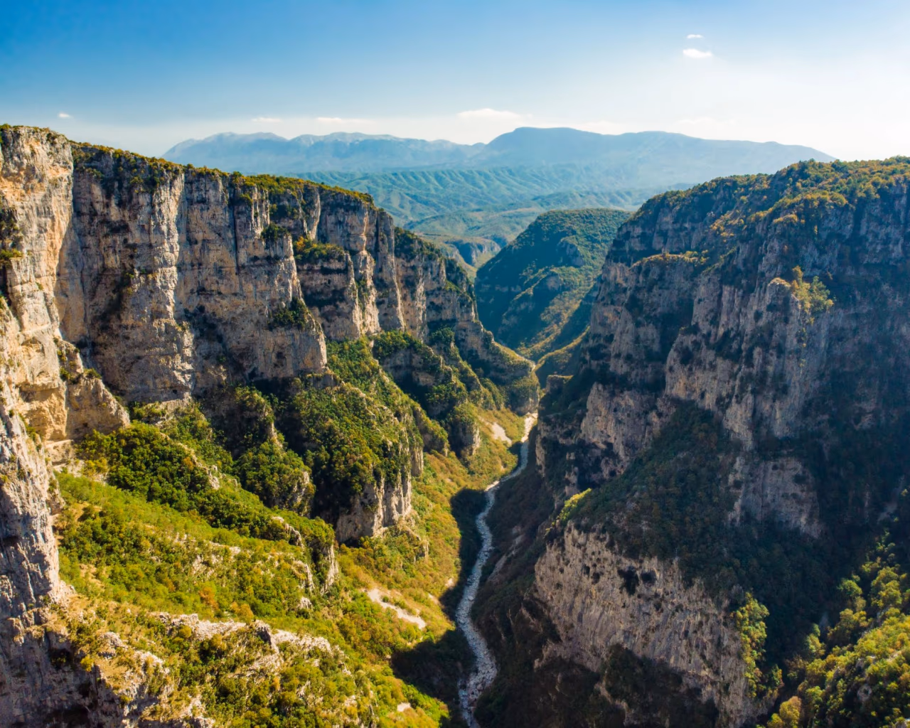 Panoramic view of the spectacular deep limestone cliffs of Vikos Gorge under a clear blue sky in Zagori, Greece