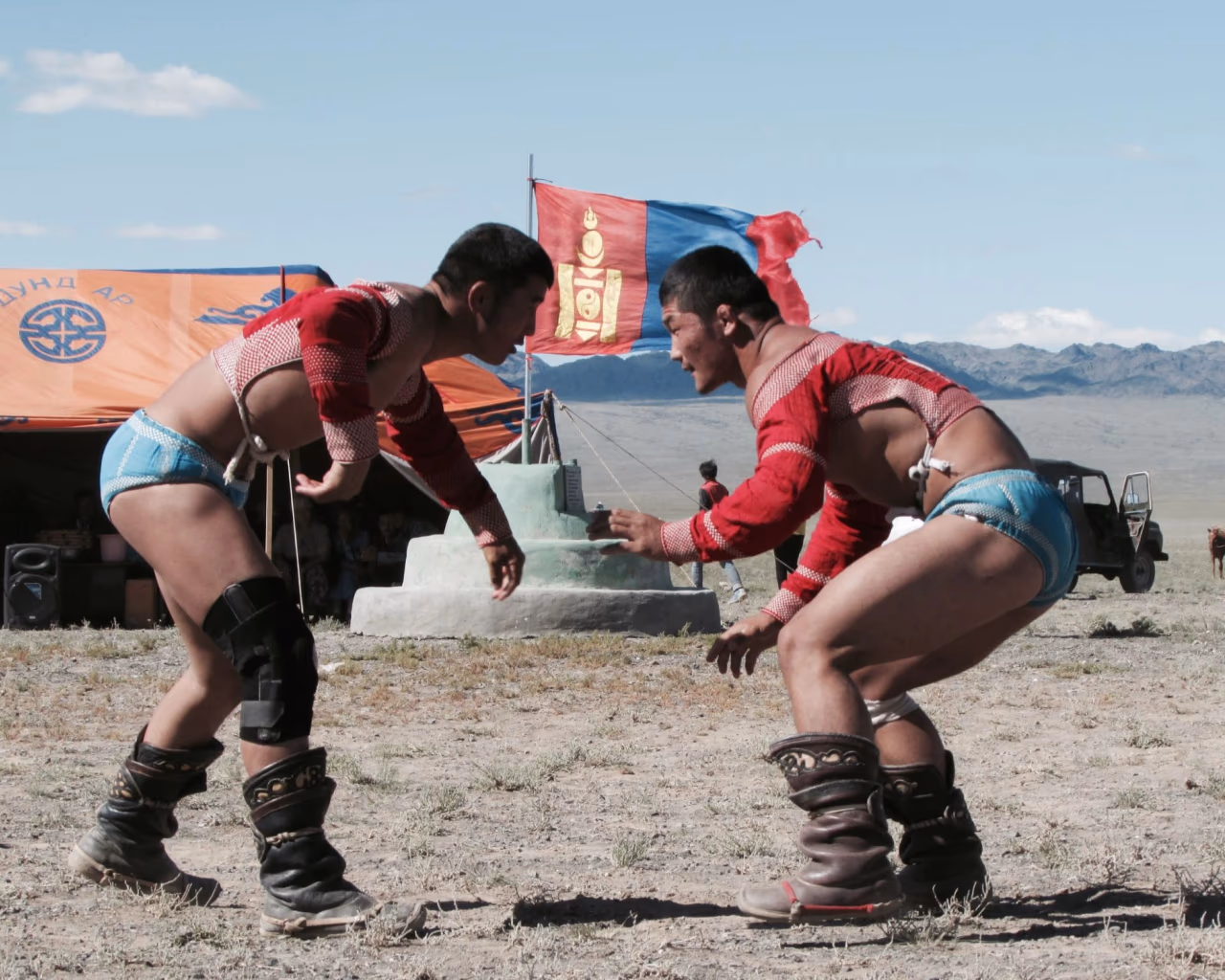 Elder and younger Mongolian locals in colorful deels sit on the grasslands, showcasing traditional culture and heritage.