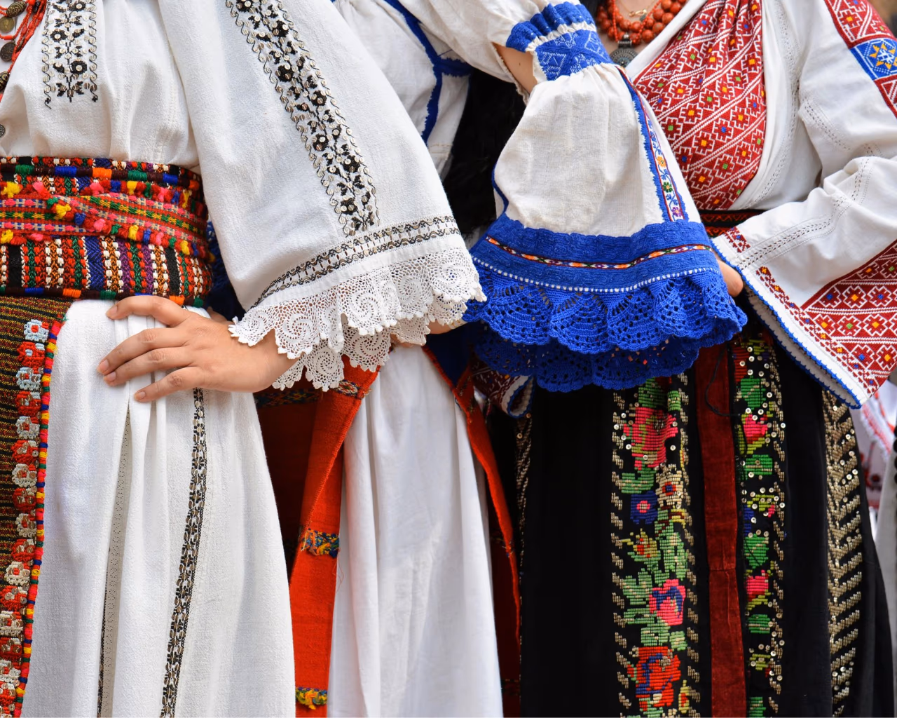 Traditional Romanian folk costumes with colorful embroidery, lace, and intricate patterns.