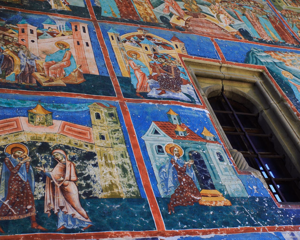 Romanian monastery wall with vibrant religious frescoes and detailed biblical scenes.