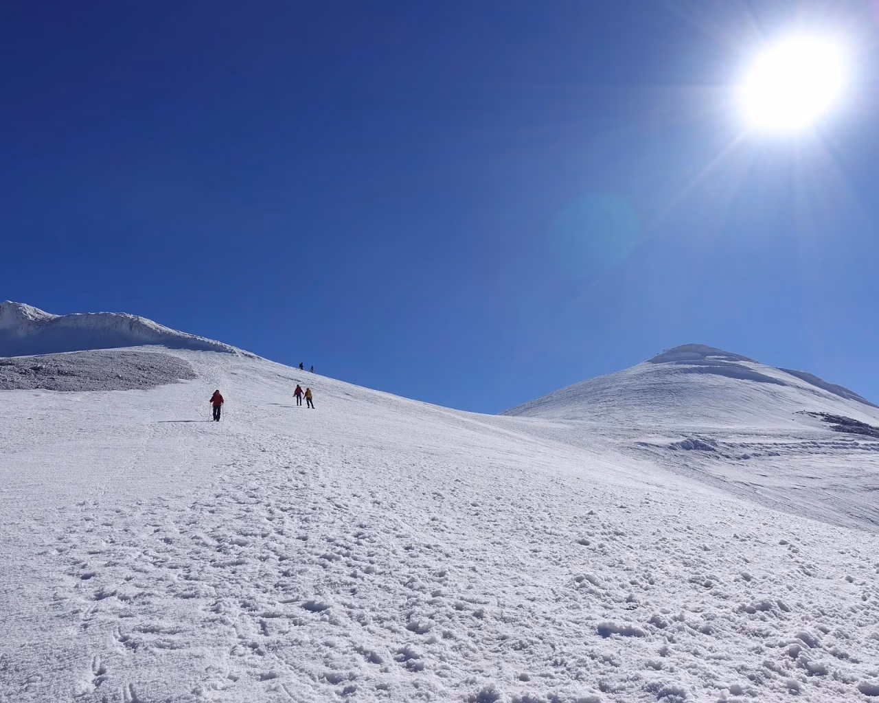 Snow-covered slopes of Mount Ararat under a bright sun, with climbers ascending.