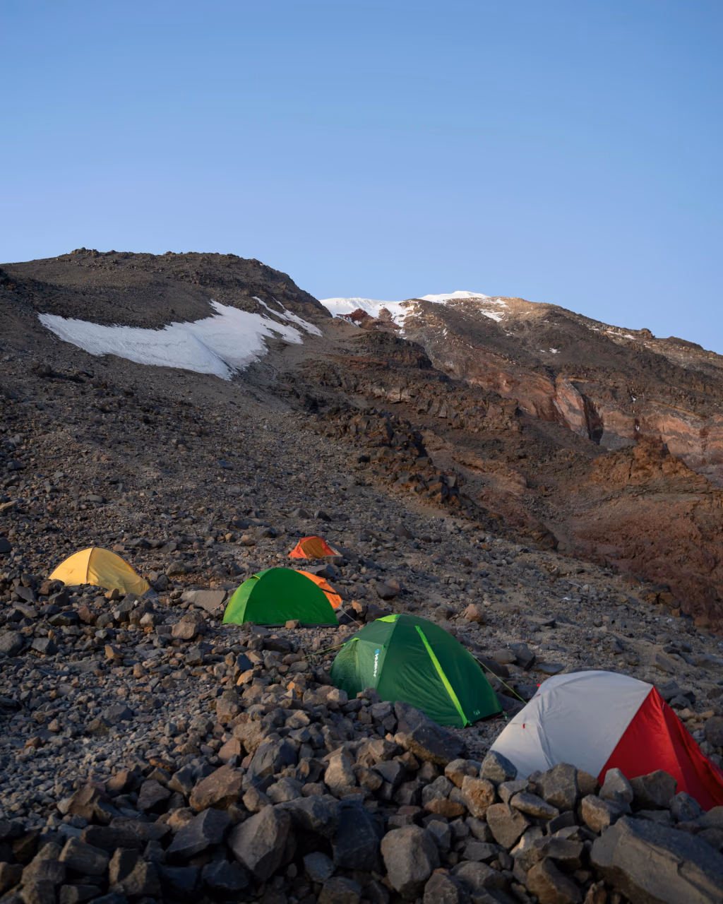 A high-altitude campsite on Mount Ararat, with colorful tents on rocky terrain.