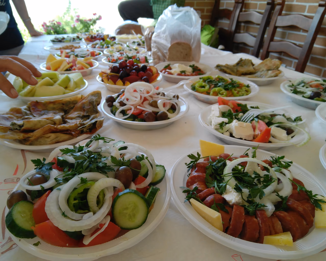 Assorted Balkan meze plates with salads, meats, cheese and fresh fruit laid out on table