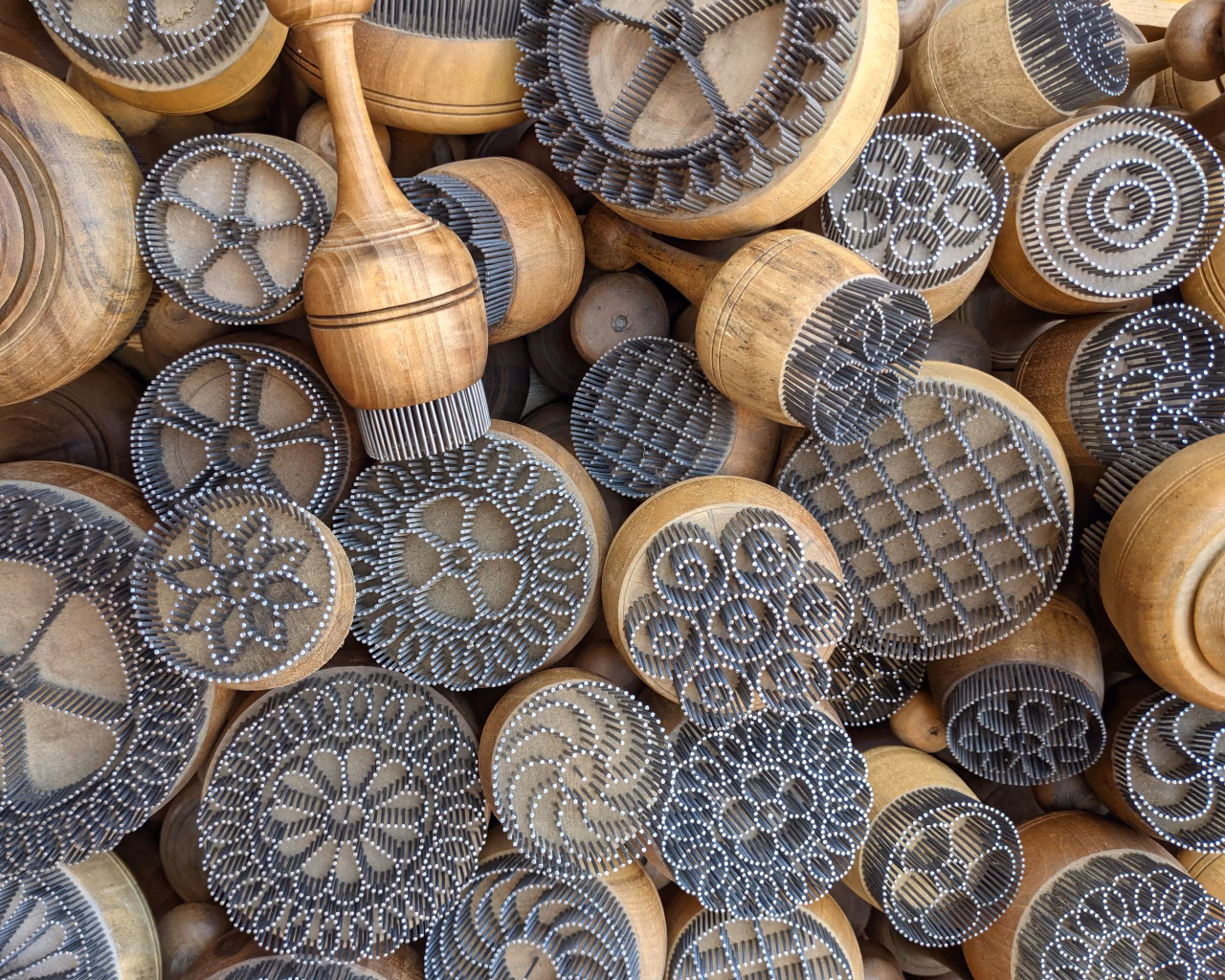 Intricate Uzbek bread stamps displayed at a market in Uzbekistan.