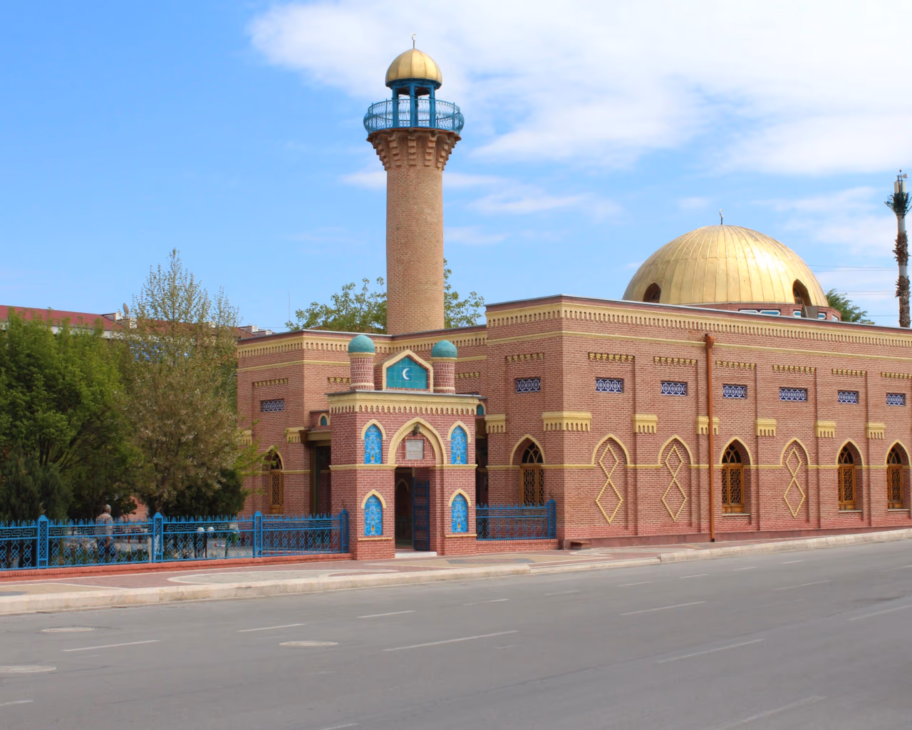 Came Mosque in Nakhchivan with golden dome and red-brick facade under a soft sky.