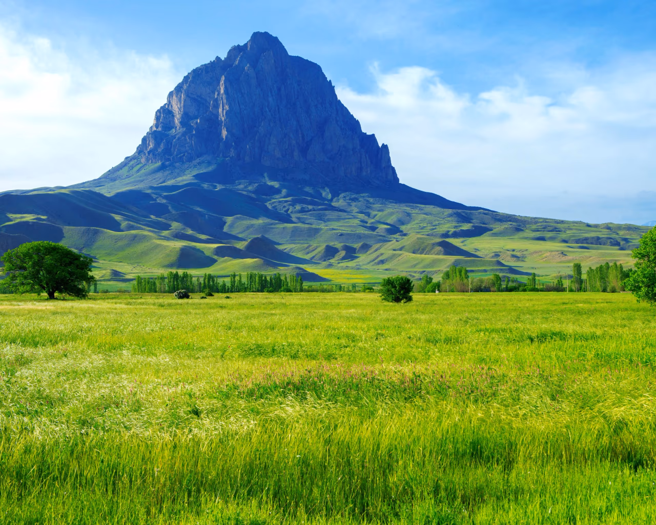 Haçadağ Mountain rises over lush Nakhchivan meadows under a bright blue sky.