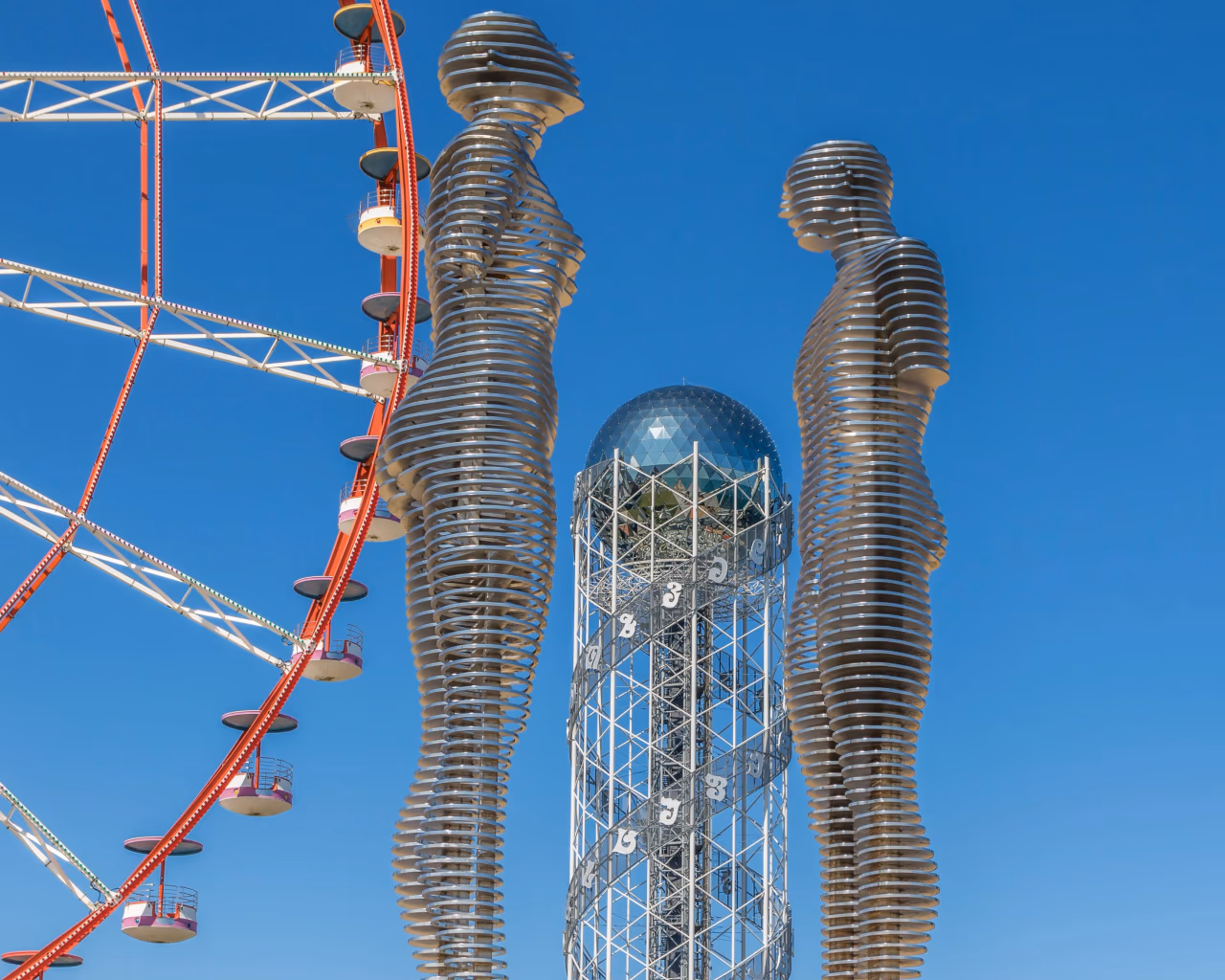 Ali and Nino moving statue with Ferris wheel and Alphabet Tower on Batumi Seaside Boulevard, Georgia