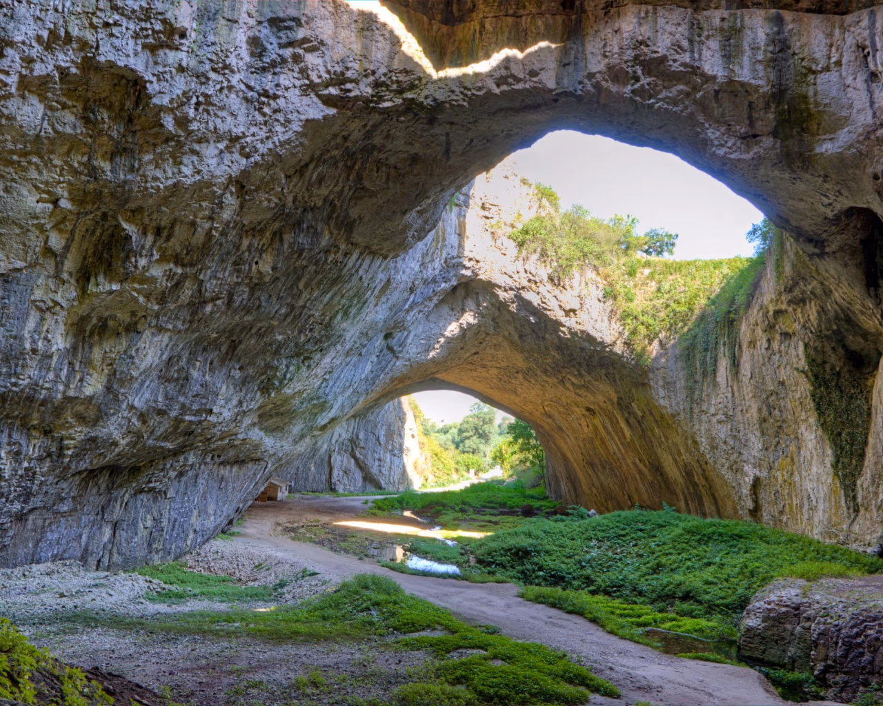 Devetashka Cave in Bulgaria - The stunning Devetashka Cave with massive rock arches and lush greenery inside.