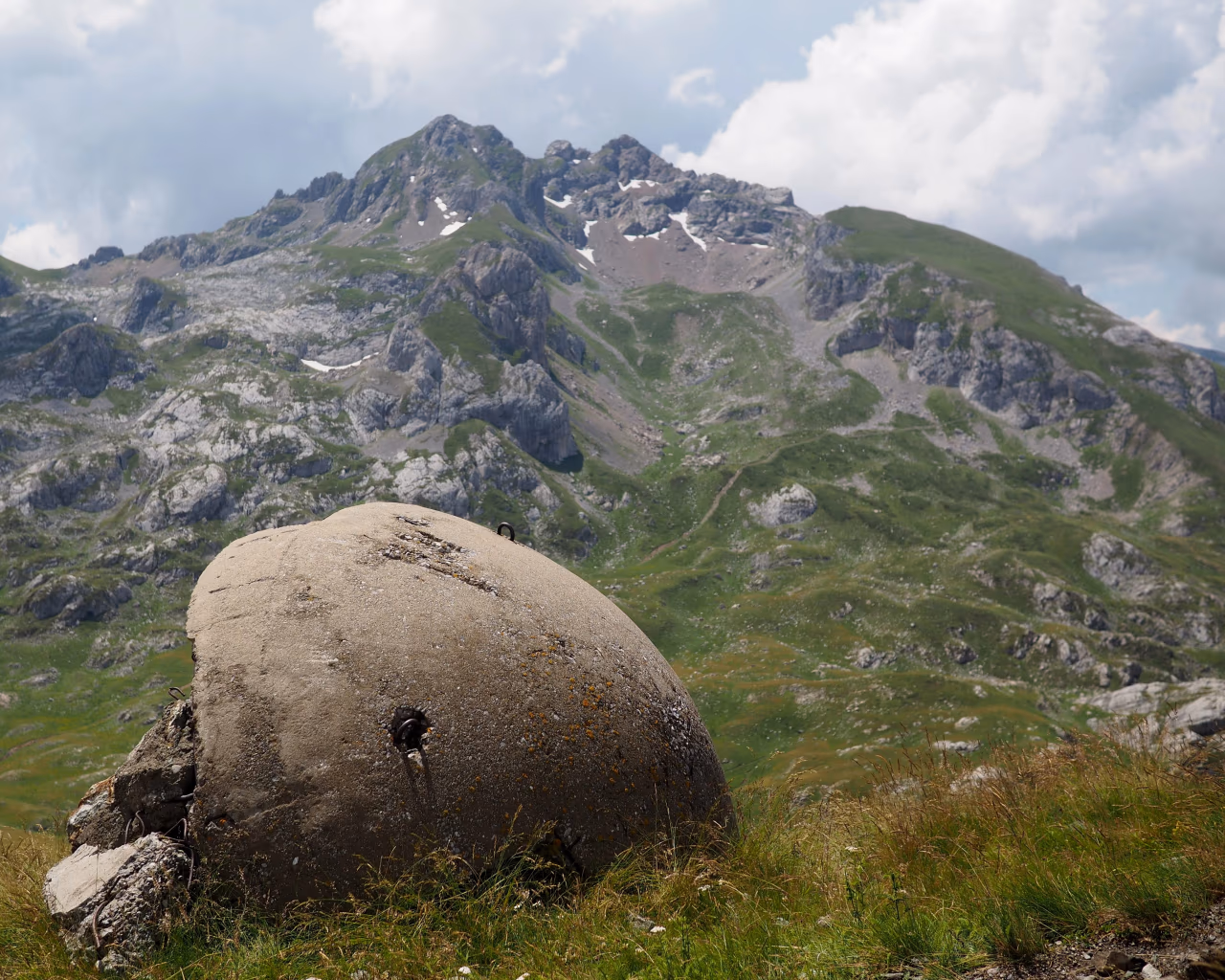 Bunker in High Scardus – A weathered concrete bunker sits in alpine meadows, rugged mountains rising in the background.