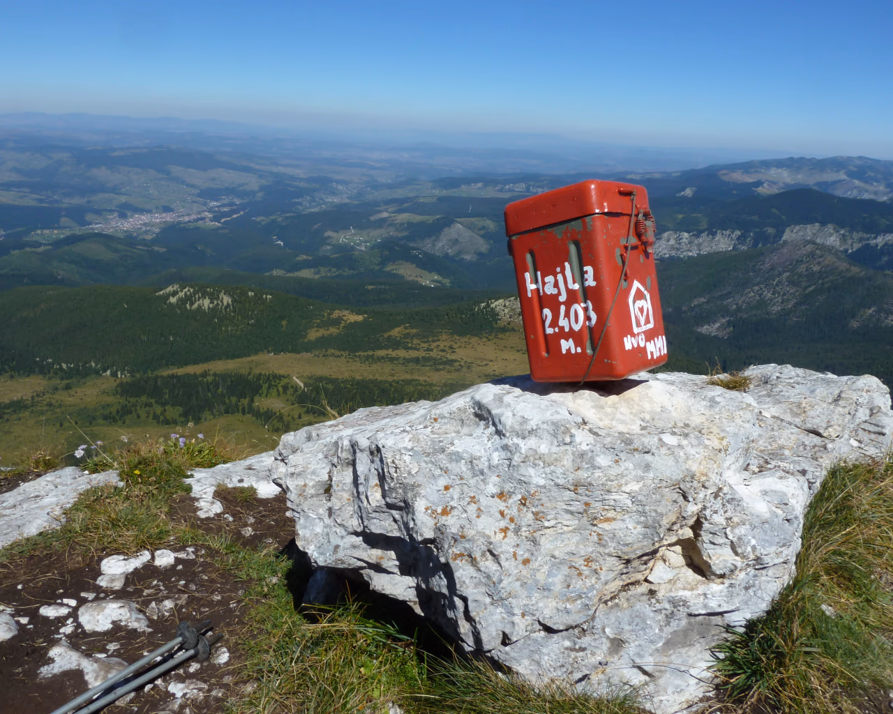 A red summit box atop Mount Hajla (2,403m), offering panoramic views over the rolling green valleys below.