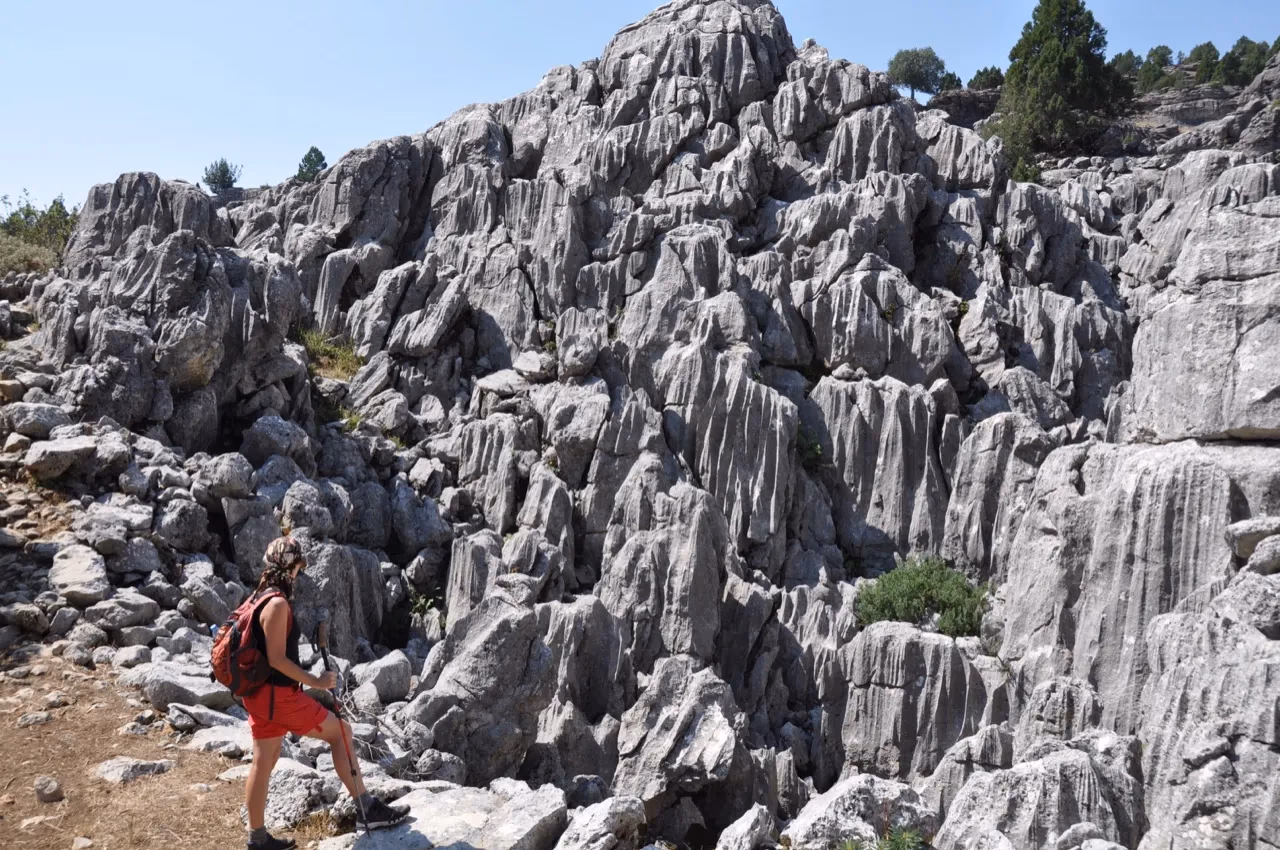 A hiker in red shorts looks up at jagged rock formations on the St. Paul Trail.