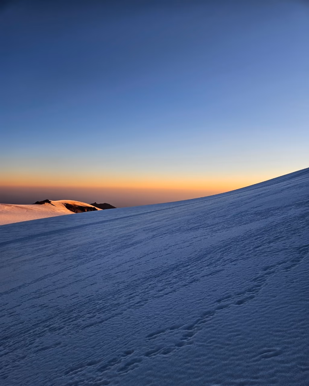 Early morning light over snow-covered slopes of Mount Kazbek, no climbers in view.