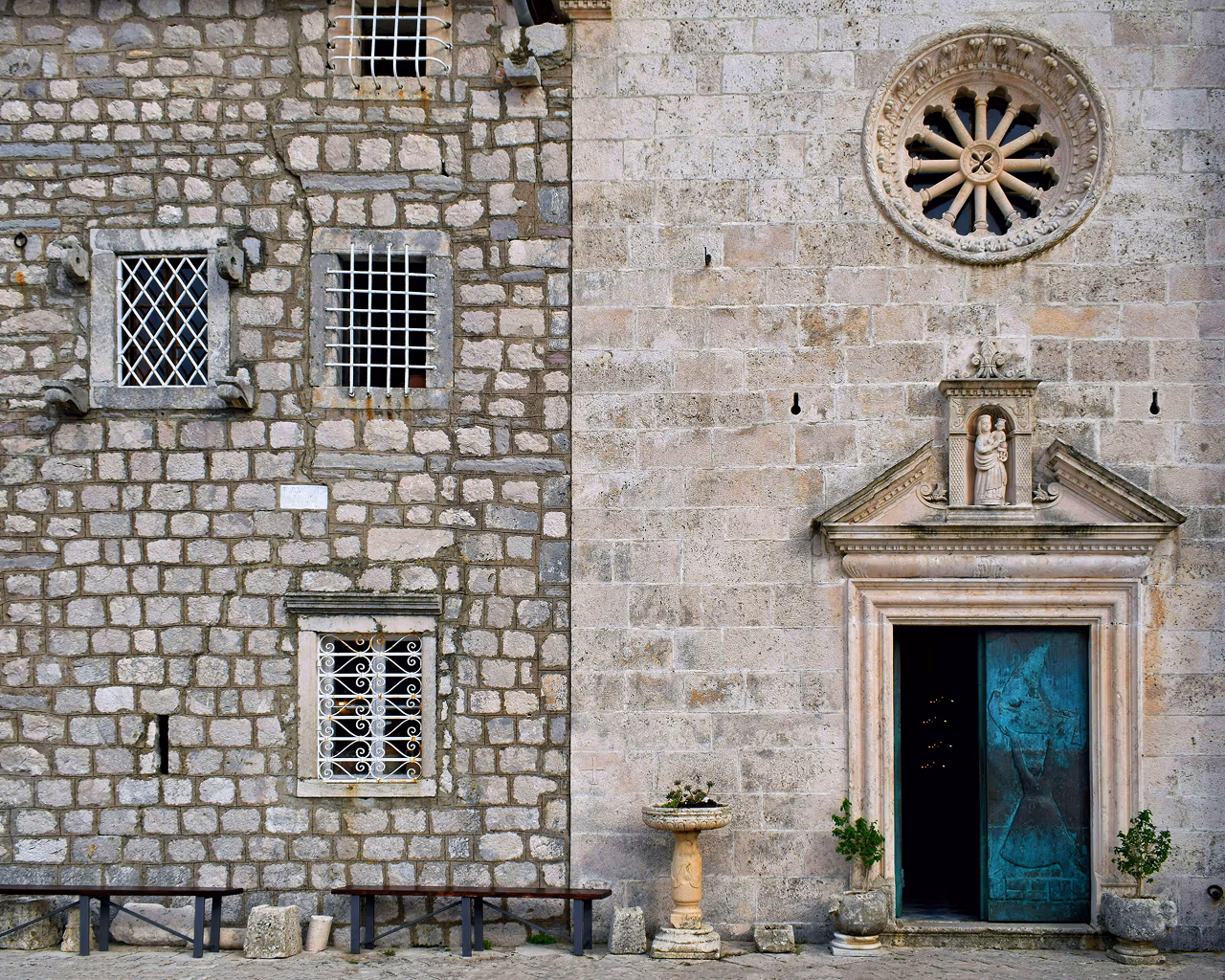A close-up of a stone-built historic church and residence in Perast, Montenegro, featuring intricate architectural details.