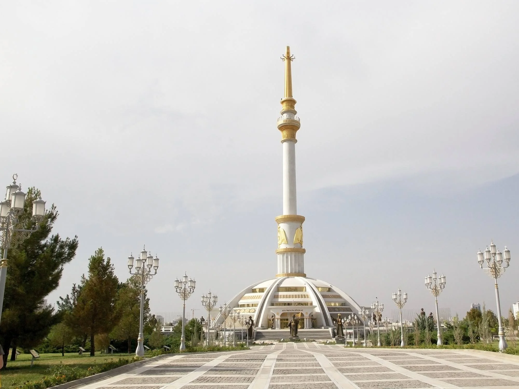 Independence Monument of Turkmenistan rising above a tiled plaza lined with ornate lamp posts, Ashgabat