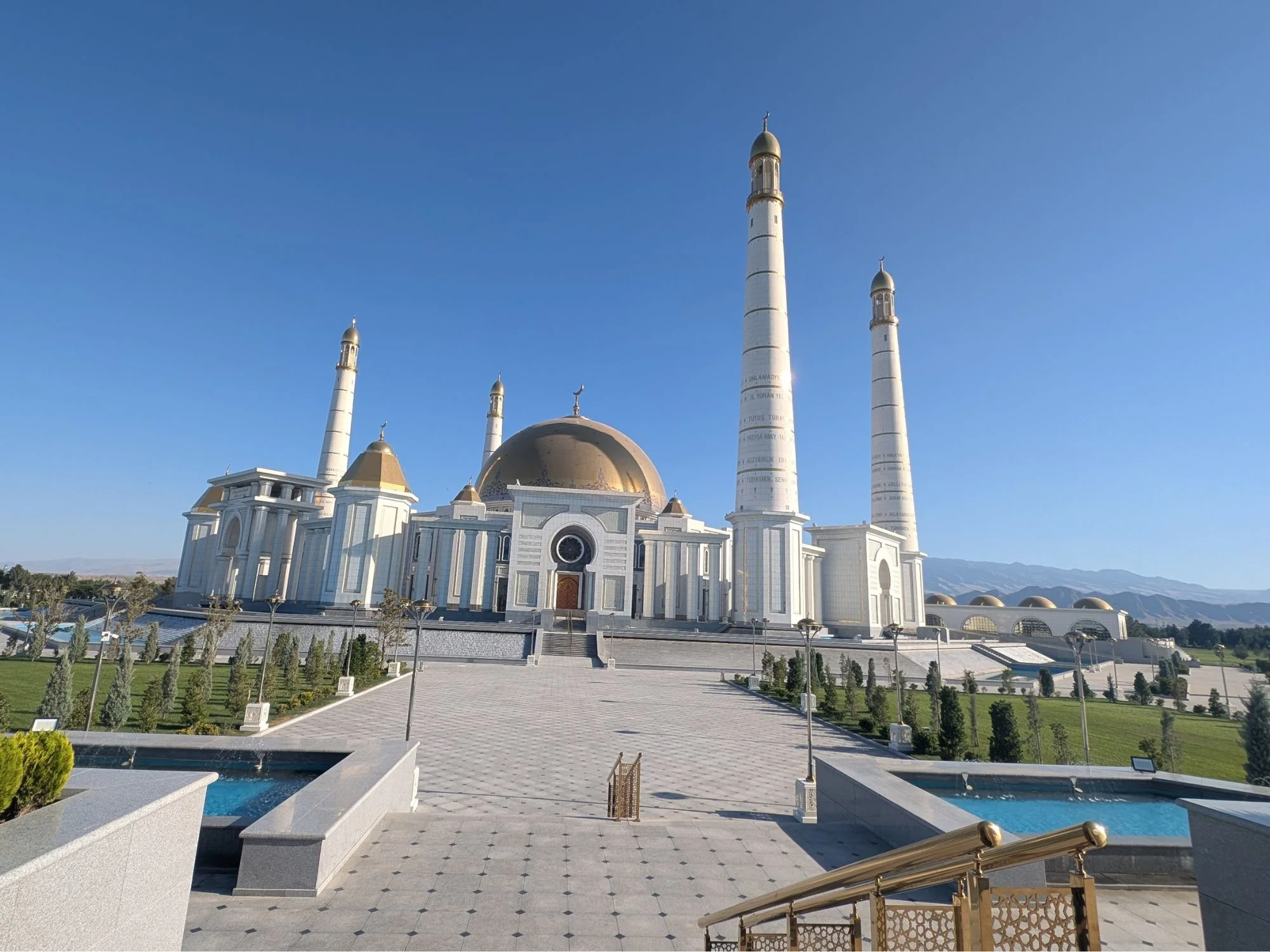 Turkmenbashy Ruhy Mosque with gold dome and four minarets, seen across its marble forecourt