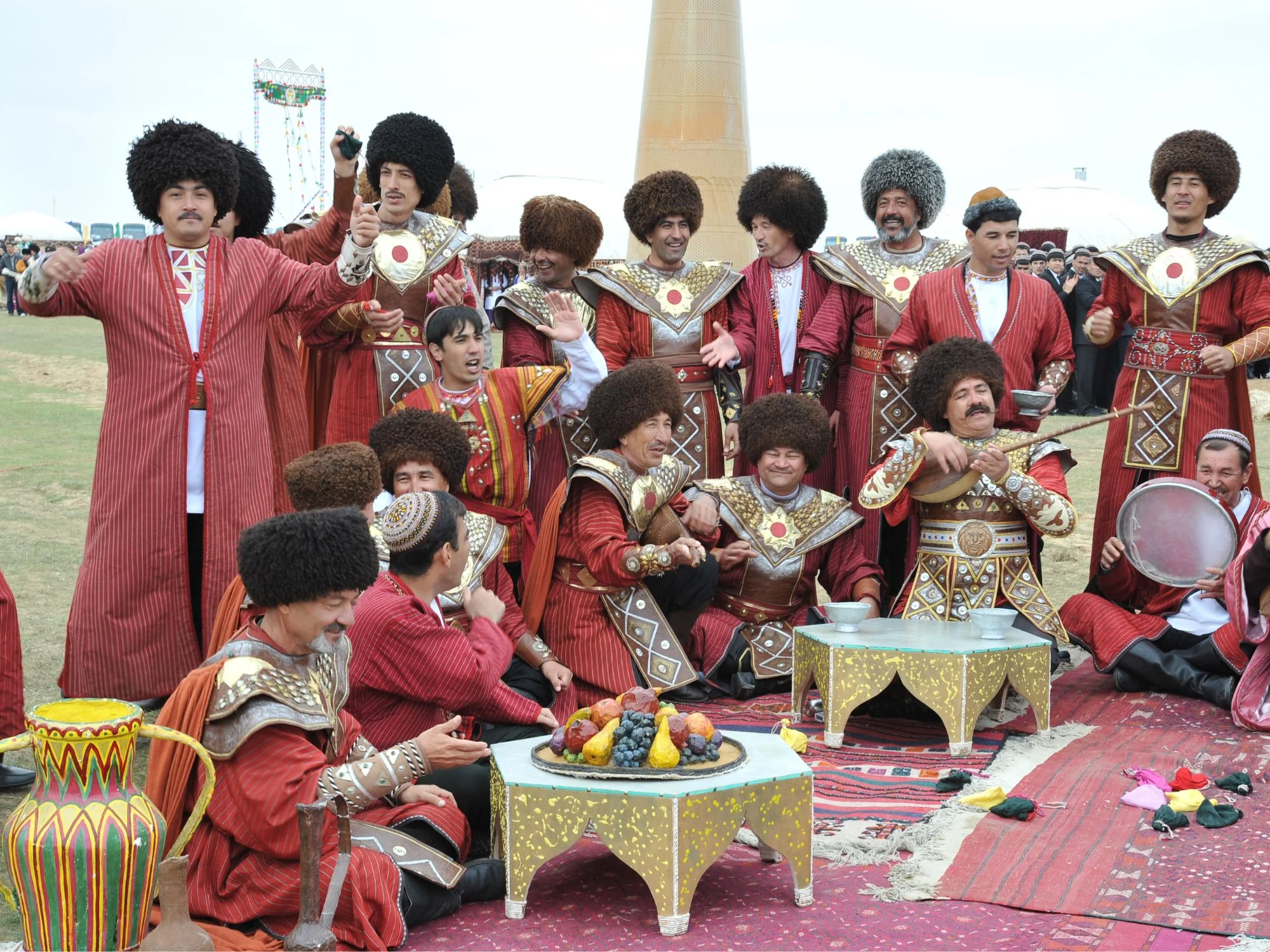 Turkmen men in red robes and sheepskin hats singing and playing music at a Novruz gathering