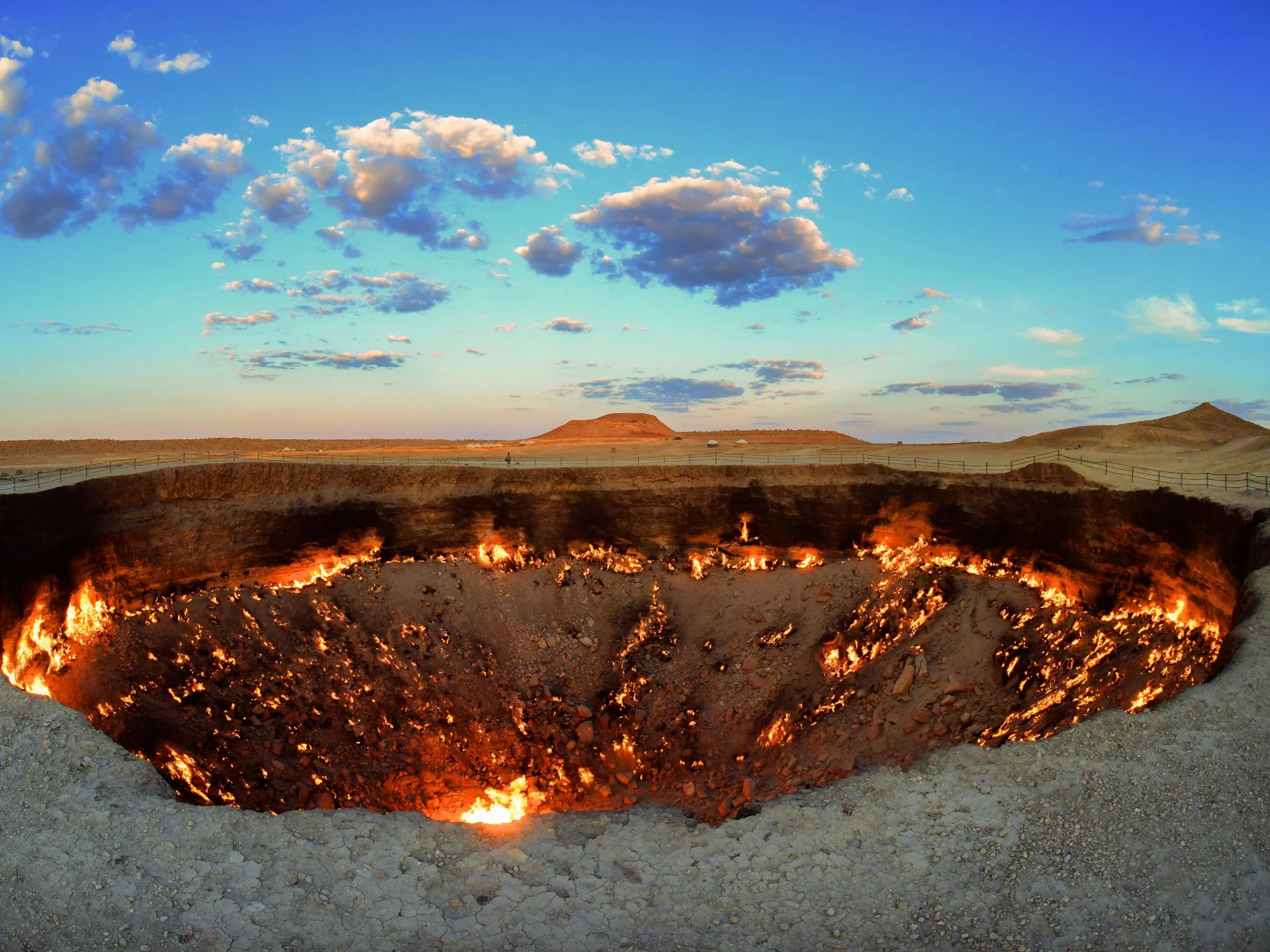 Flames burning across the floor of the Darvaza Gas Crater at dusk in the Karakum Desert