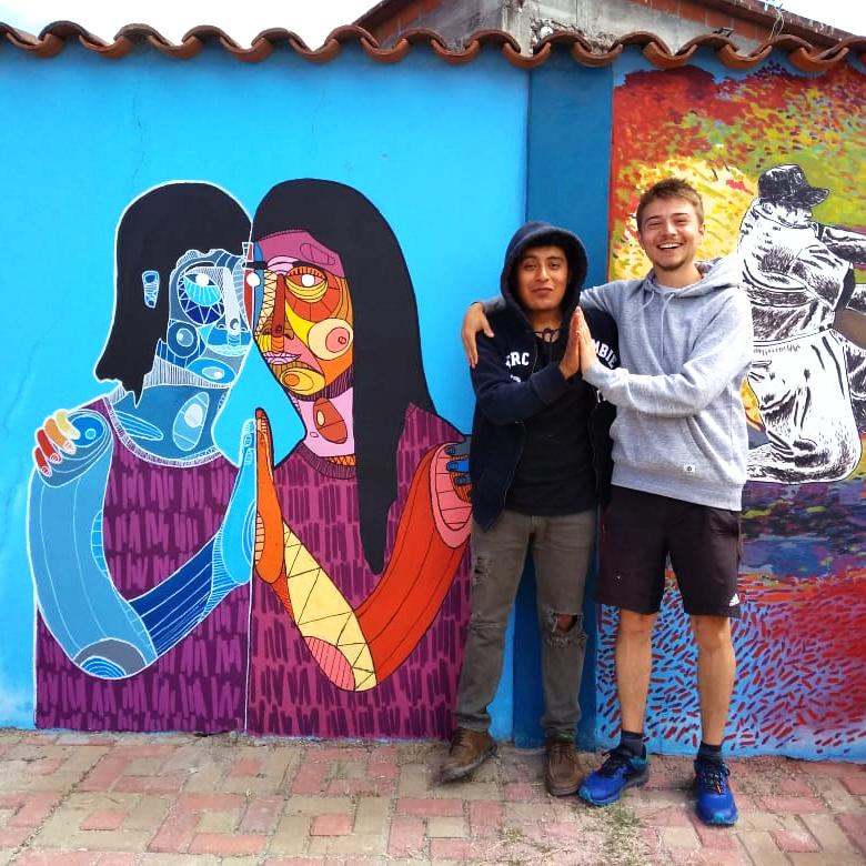 Homme et femme au Mexique devant une fresque de deux femmes se tenant les mains