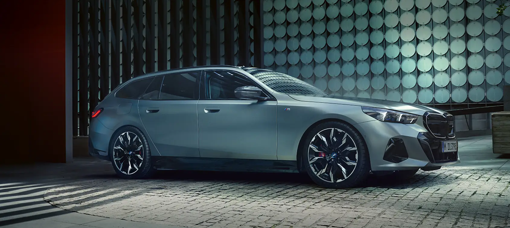 BMW i5 Touring M Sport in matter Lackierung vor moderner Architektur – BMW Wolter & Steiner in Neubrandenburg, Waren und Prenzlau