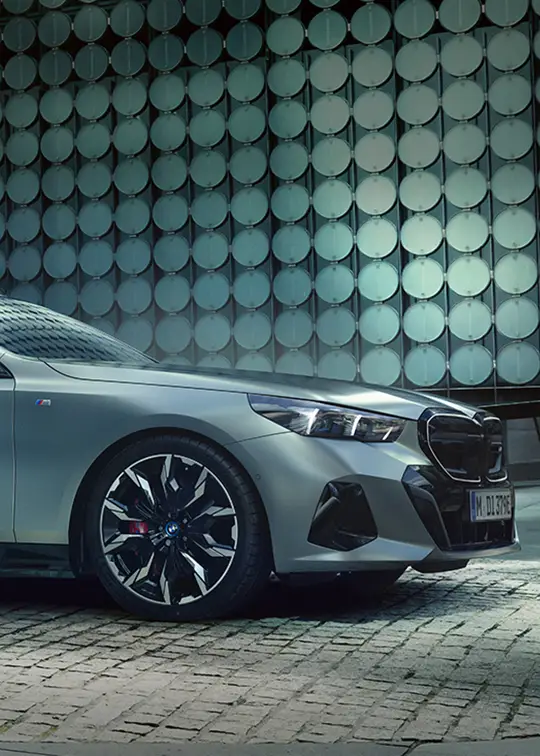 BMW i5 Touring M Sport in matter Lackierung vor moderner Architektur – BMW Wolter & Steiner in Neubrandenburg, Waren und Prenzlau