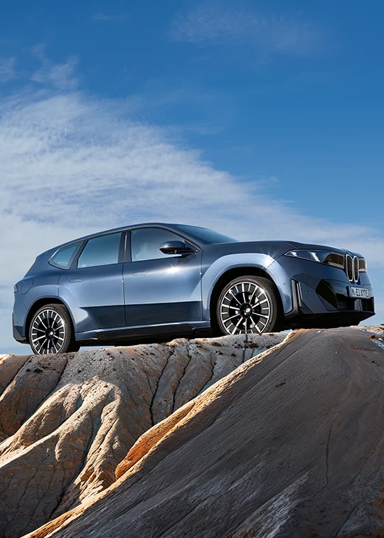 Der neue BMW iX3 in blau-metallic auf felsigem Höhenzug unter weitem Himmel – BMW Wolter & Steiner in Neubrandenburg, Waren und Prenzlau