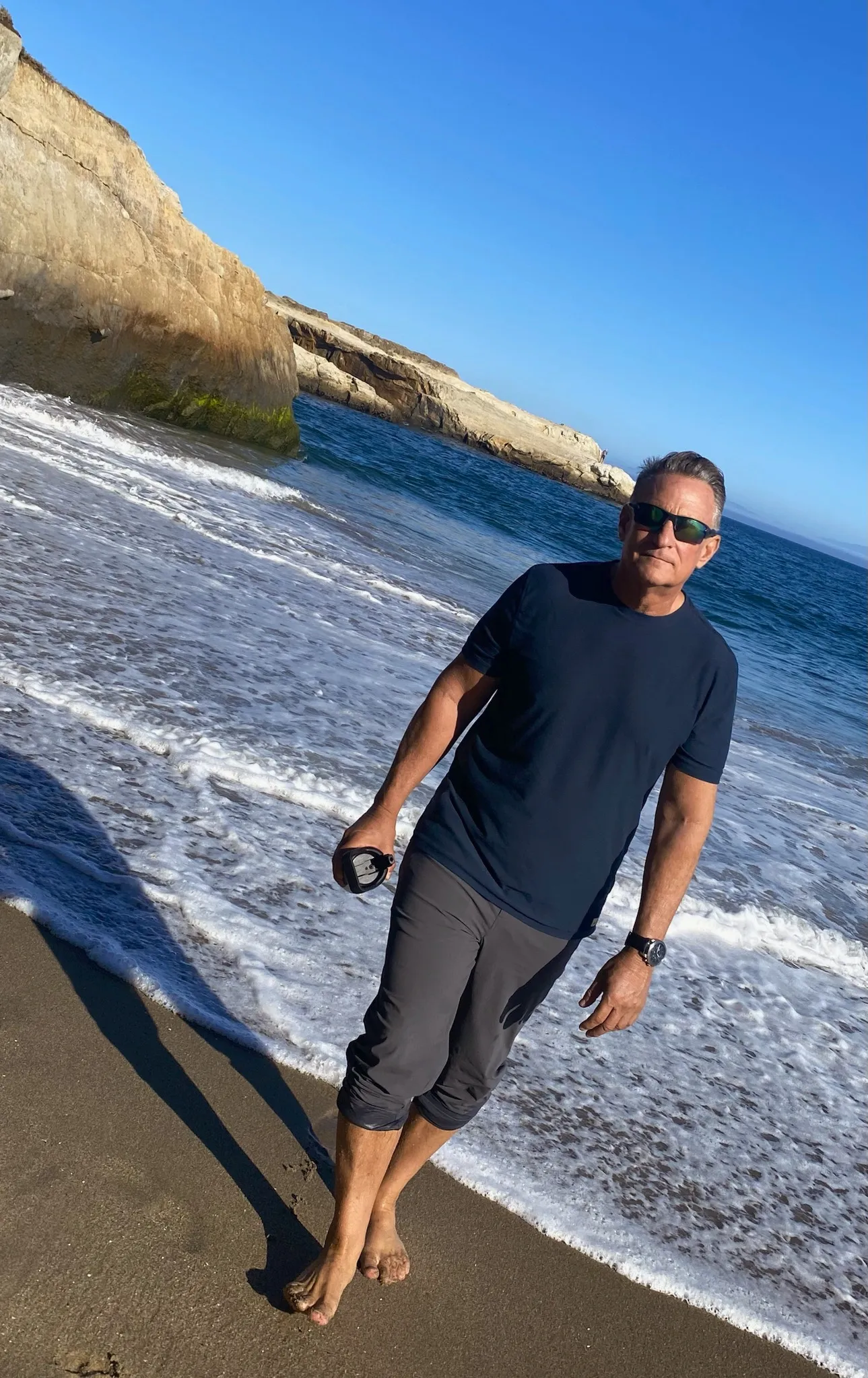 A man walking on the beach with sunglasses