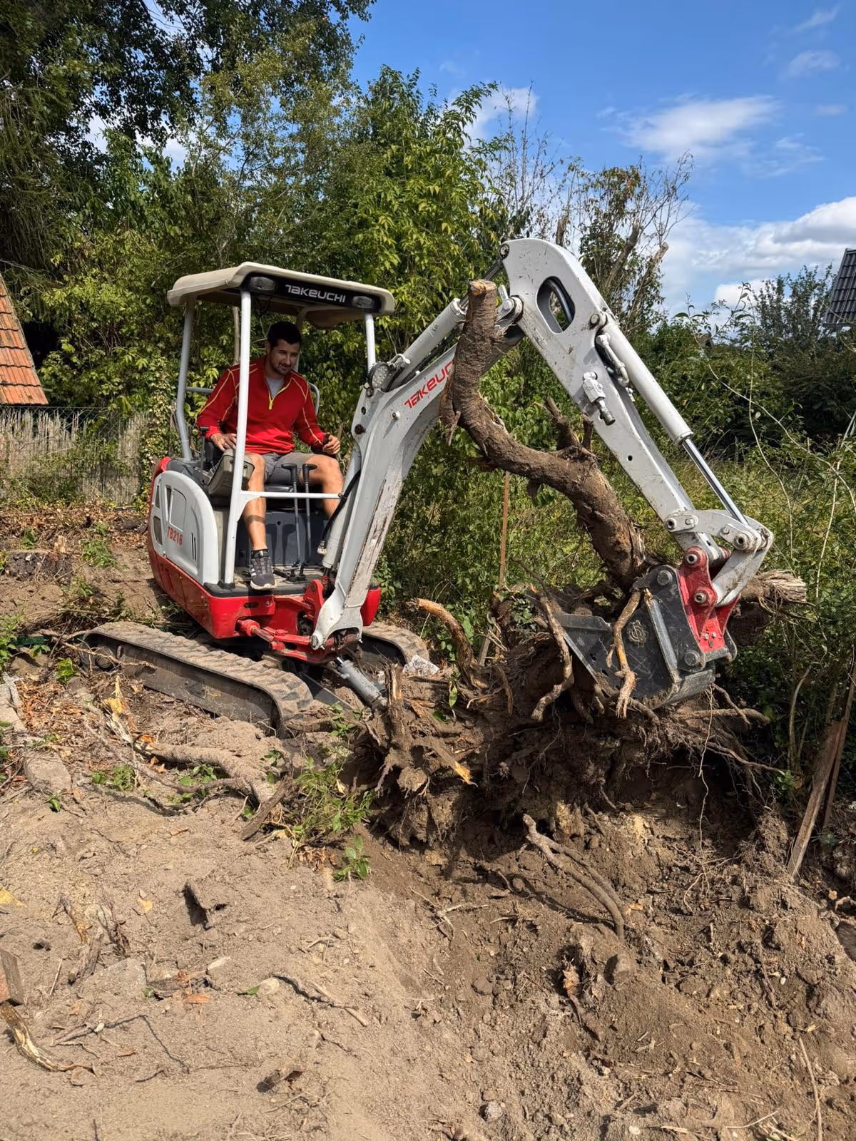 Arbeiter in rotem T-Shirt sitzt in Bagger