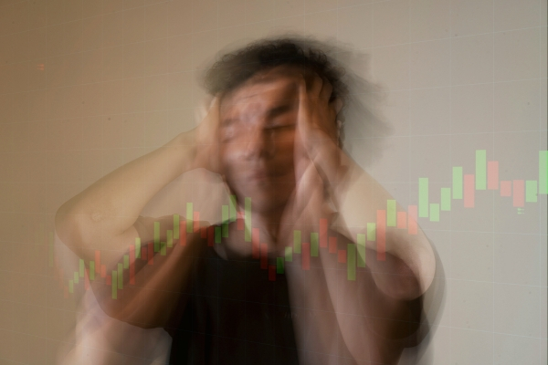 Blurred stressed man with stock chart overlay symbolizing emotional instability in trading