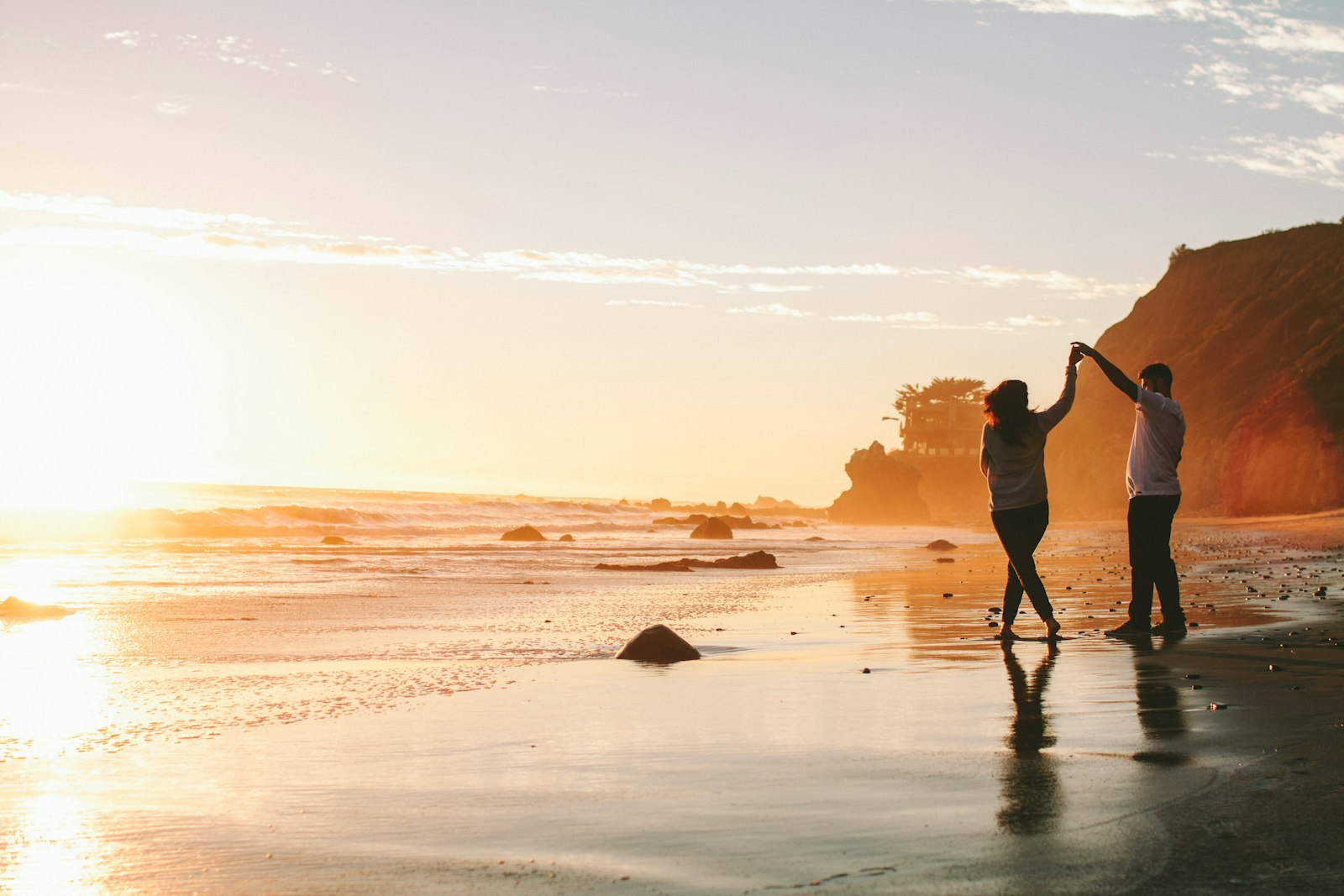 Couple holding hands on a Dubai beach at golden hour