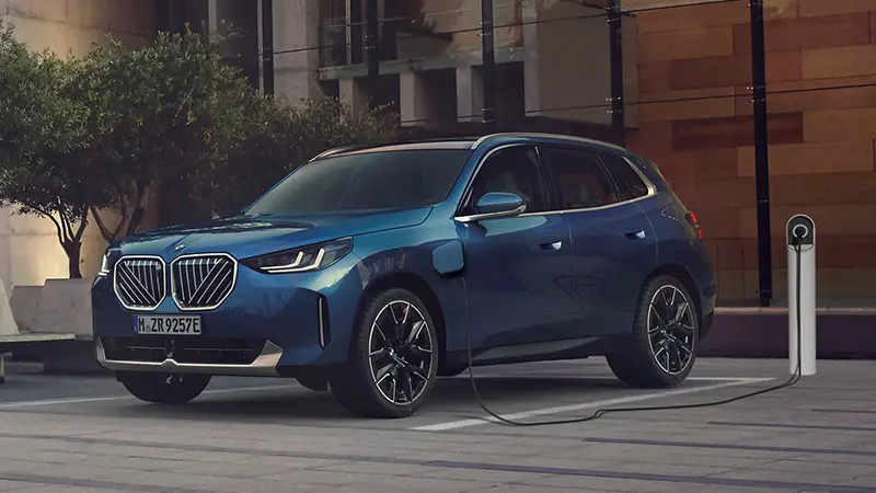 Blauer BMW SUV lädt an moderner E-Ladesäule in urbaner Umgebung – BMW Baum Automobile in Bad Neuenahr-Ahrweiler
