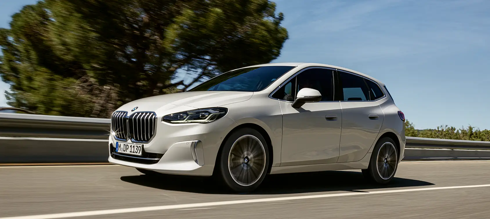 Weißer BMW 218i Active Tourer fährt auf sonniger Landstraße – BMW Baum Automobile in Bad Neuenahr-Ahrweiler