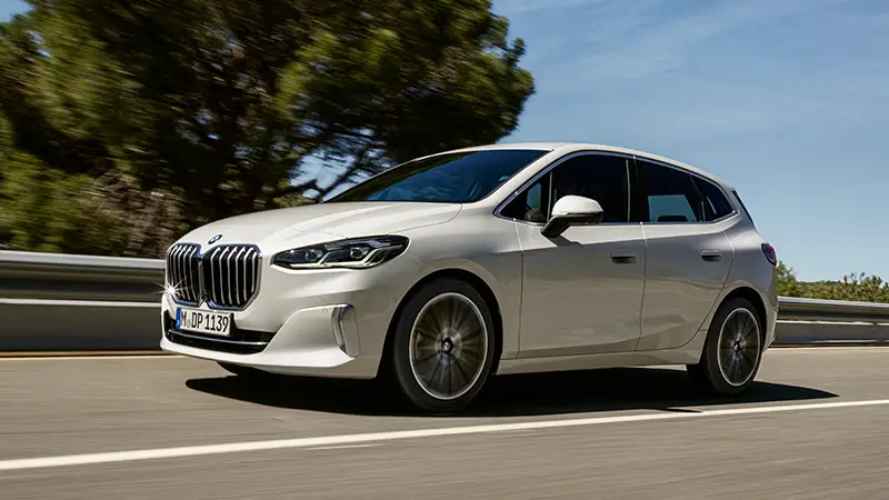 Weißer BMW 218i Active Tourer fährt auf sonniger Landstraße – BMW Baum Automobile in Bad Neuenahr-Ahrweiler