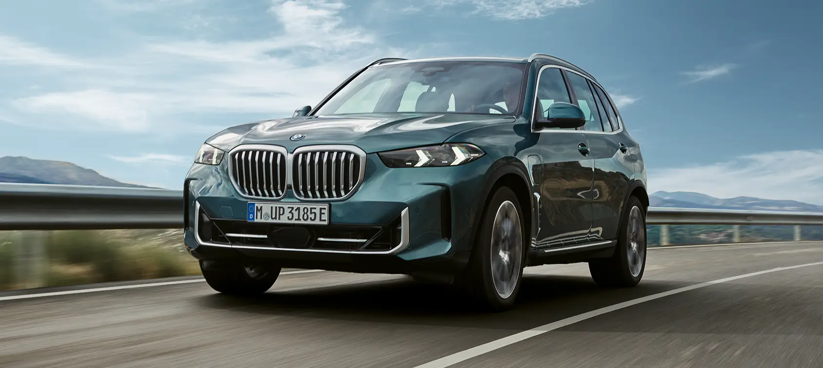 Grüner BMW X5 SUV fährt auf Landstraße bei blauem Himmel – BMW Baum Automobile in Bad Neuenahr-Ahrweiler