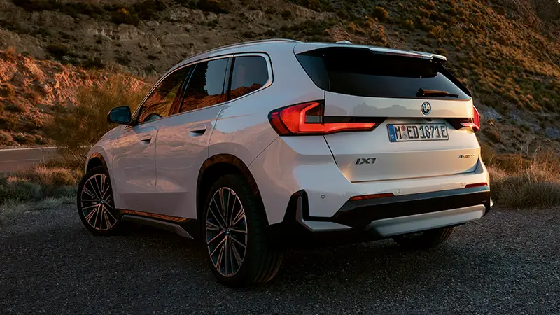 Weißer BMW iX1 geparkt in bergiger Landschaft bei Sonnenuntergang – BMW Baum Automobile in Bad Neuenahr-Ahrweiler
