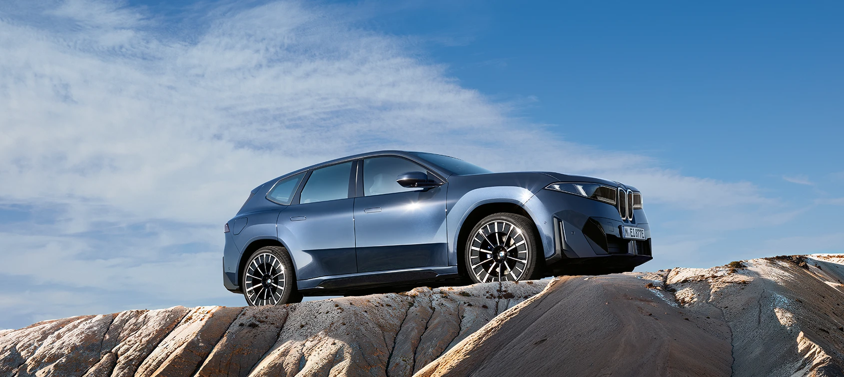 Blauer BMW iX3 Neue Klasse auf felsigem Gelände unter weitem Himmel – BMW Baum Automobile in Bad Neuenahr-Ahrweiler