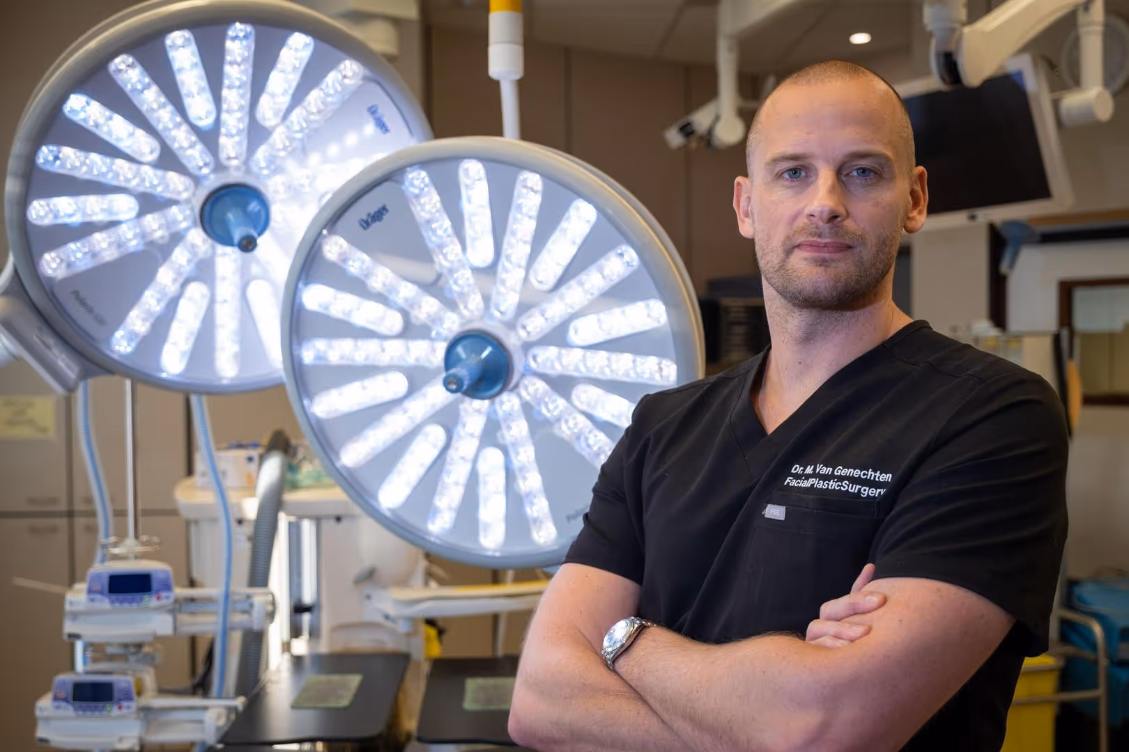 Dr. Maarten Van Genechten in chirurgisch tenue die poseert in een operatiekamer met gekruiste armen.