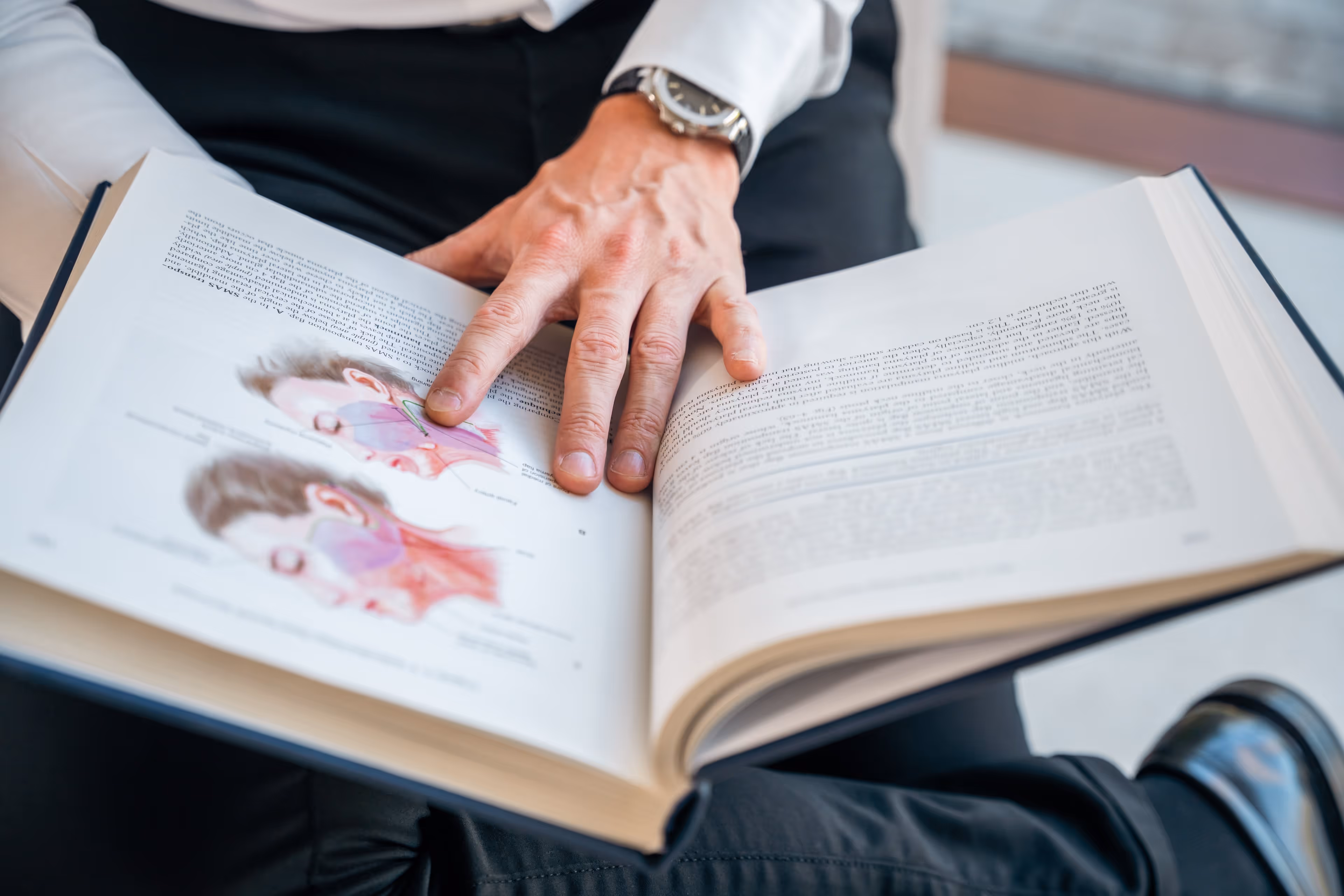 Dr. Maarten Van Genechten die door een anatomie boek bladert.