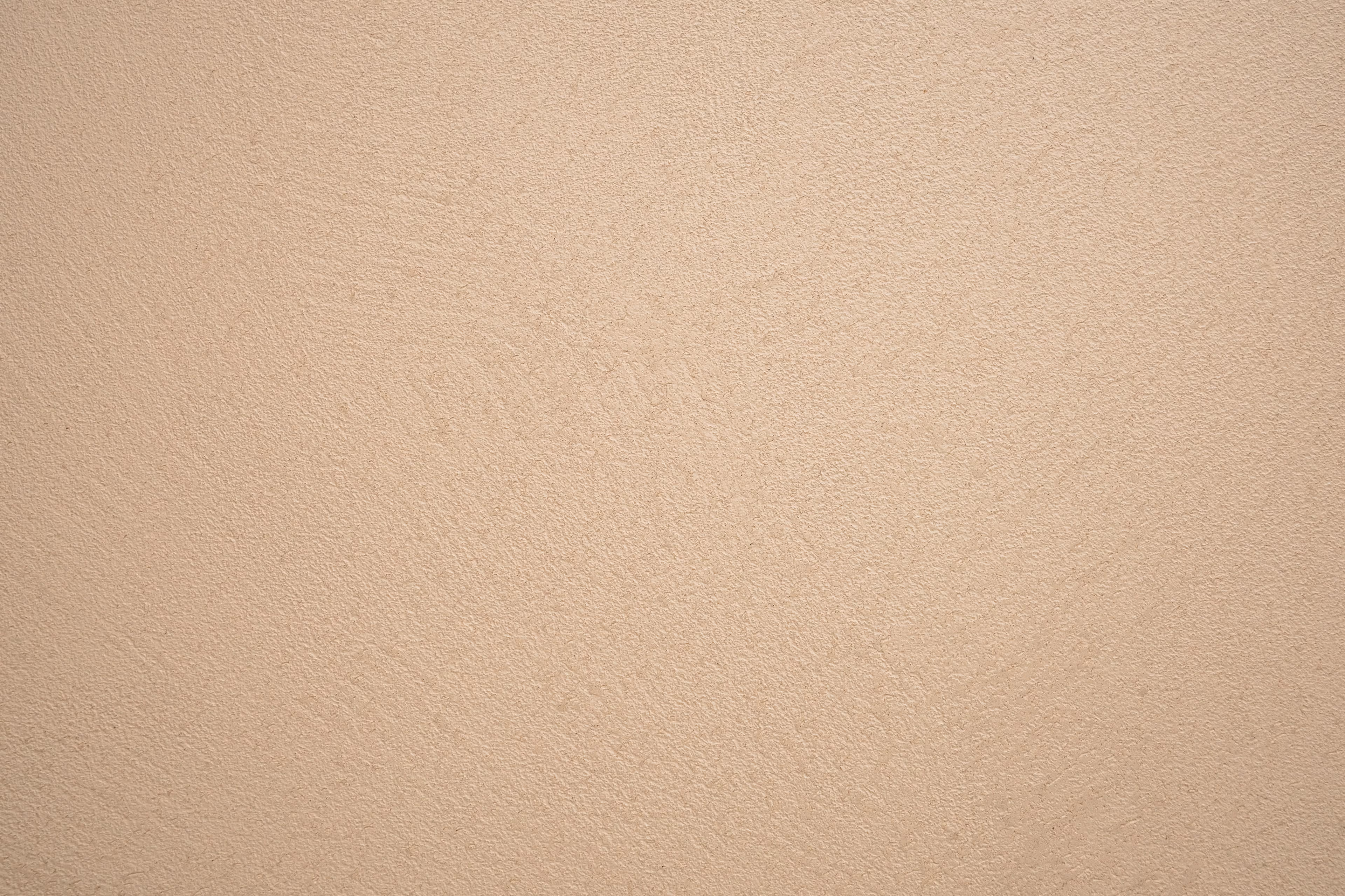 Beige gepleisterde muur met lichte textuur.