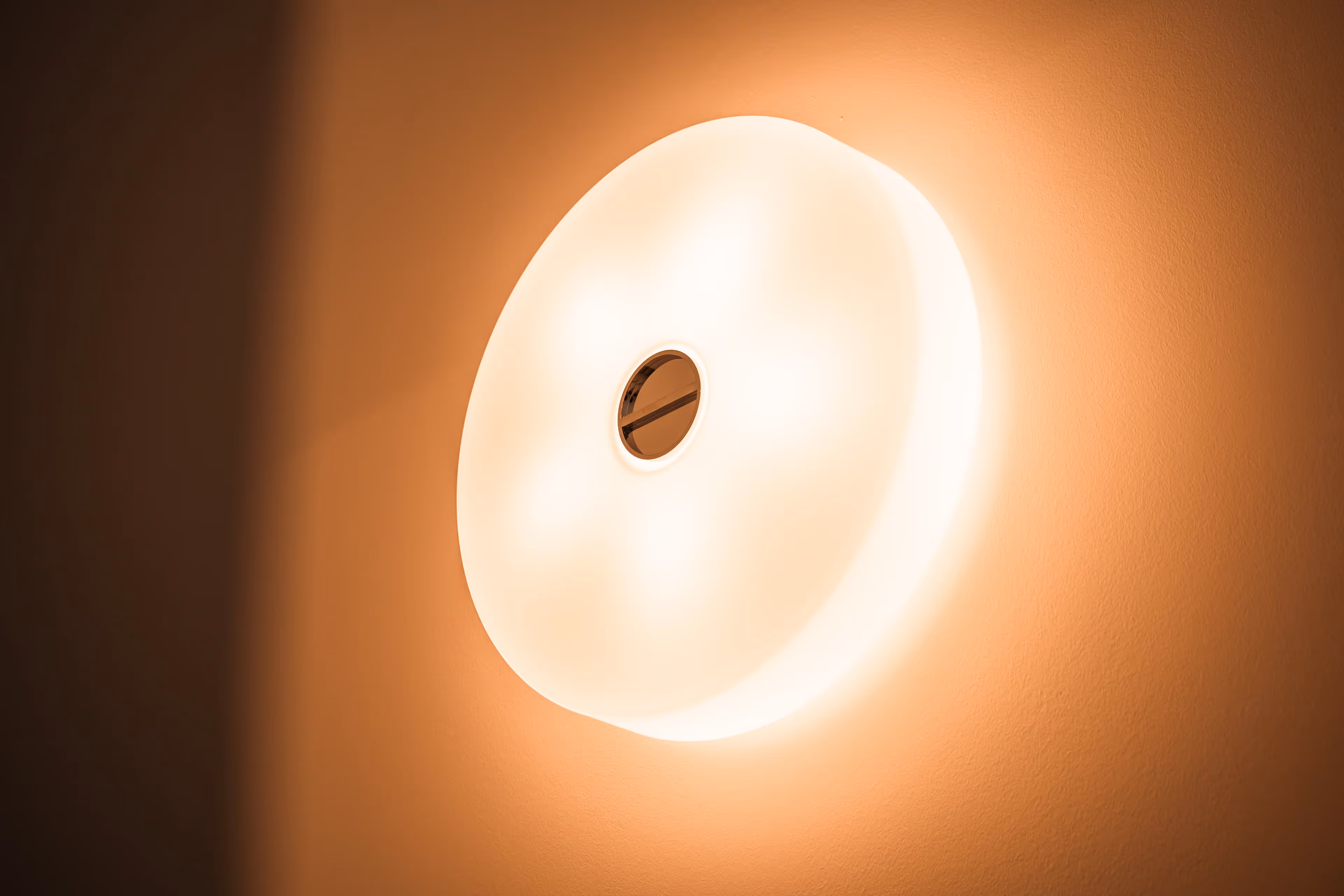 Gloeiende, cirkelvormige wandlamp die een warme lichtkleur heeft.