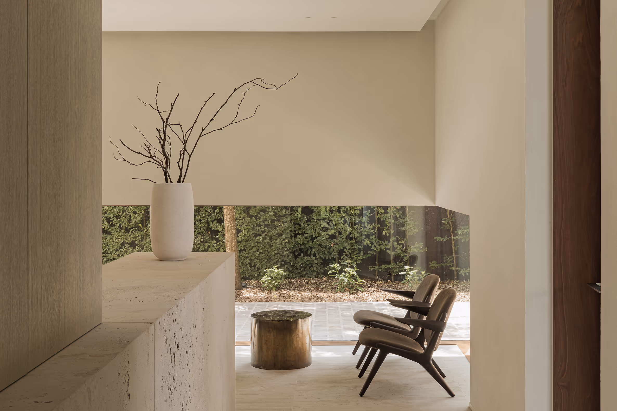 The counter of the Catershoek surgical center, with 2 chairs, coffee table and a white vase with ornamental branches on the counter from tevertine.