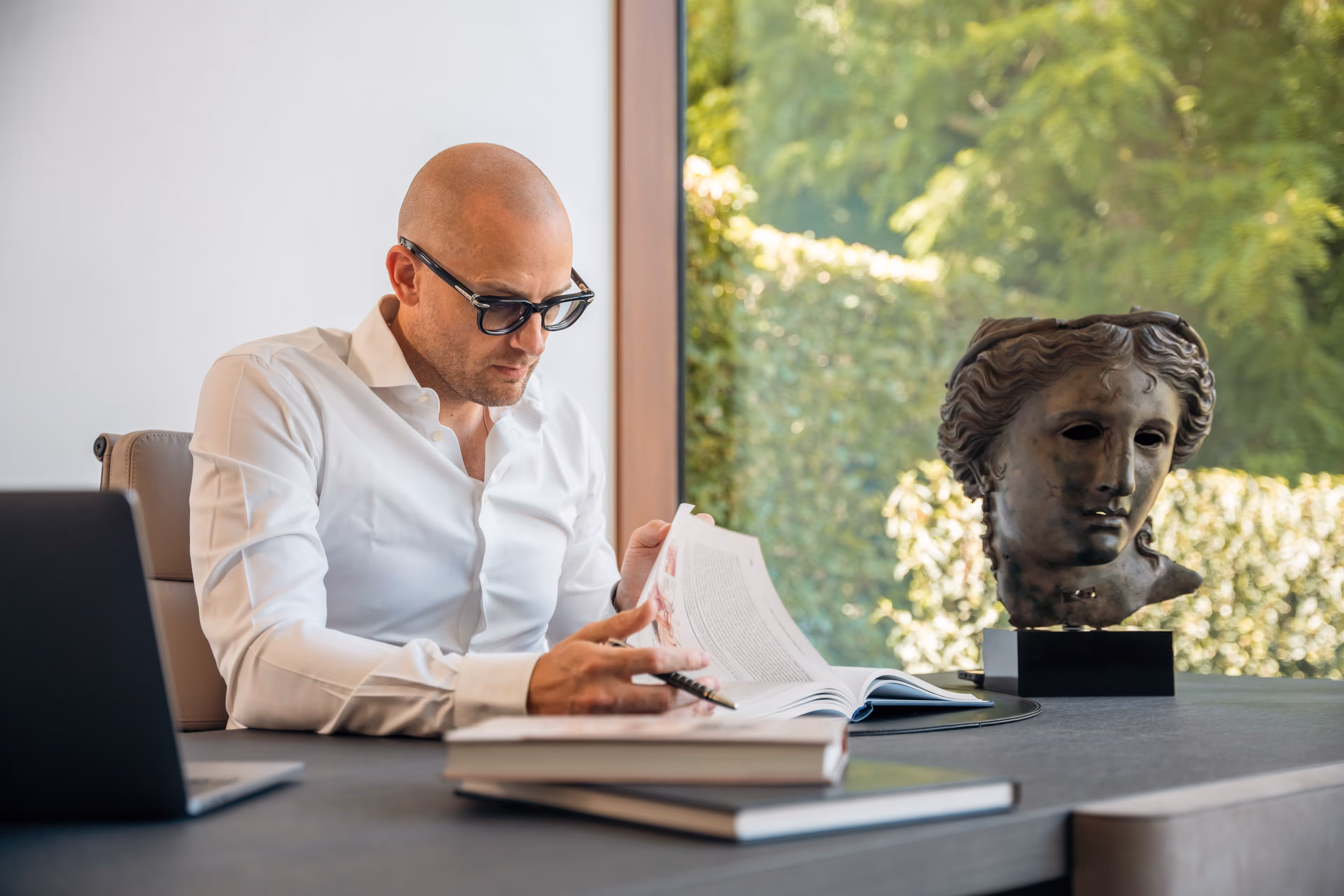 Dr. Maarten Van Genechten die aan zijn bureau zit en bladert door een boek.