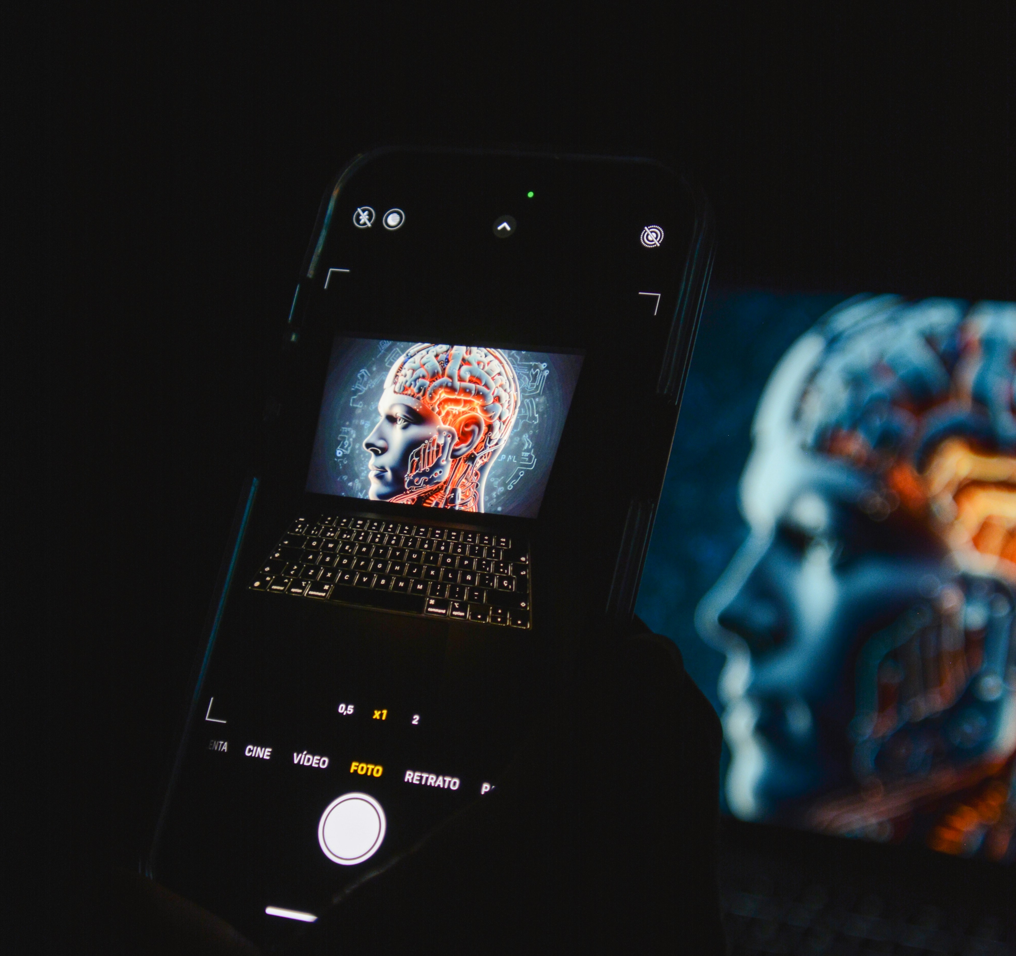 A smartphone capturing an AI-generated image of a human head with illuminated brain circuits displayed on a laptop screen, representing artificial intelligence and digital innovation.