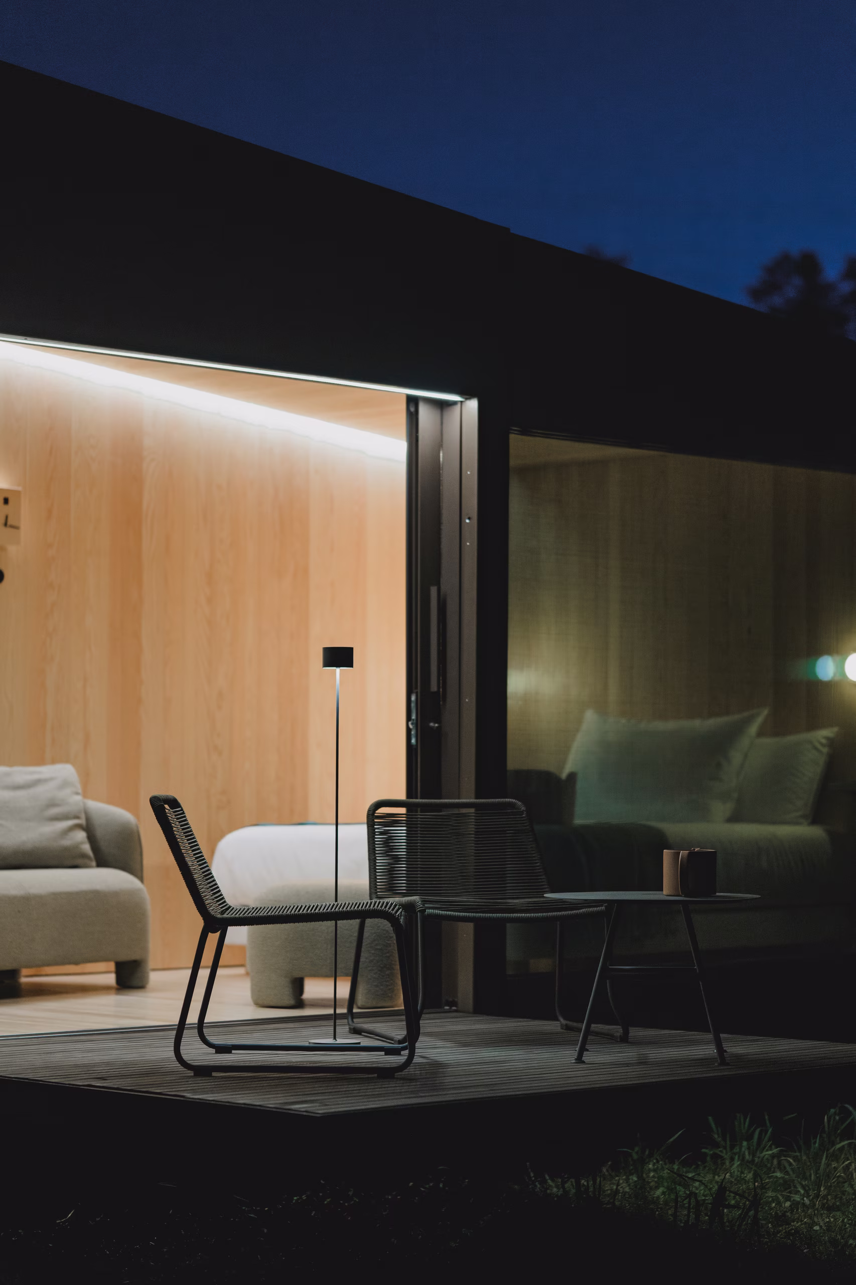 Terrazza in legno di design dell'effimero hotel a 4 stelle SNUUG illuminata al tramonto, che invita a disconnettersi e contemplare la natura.