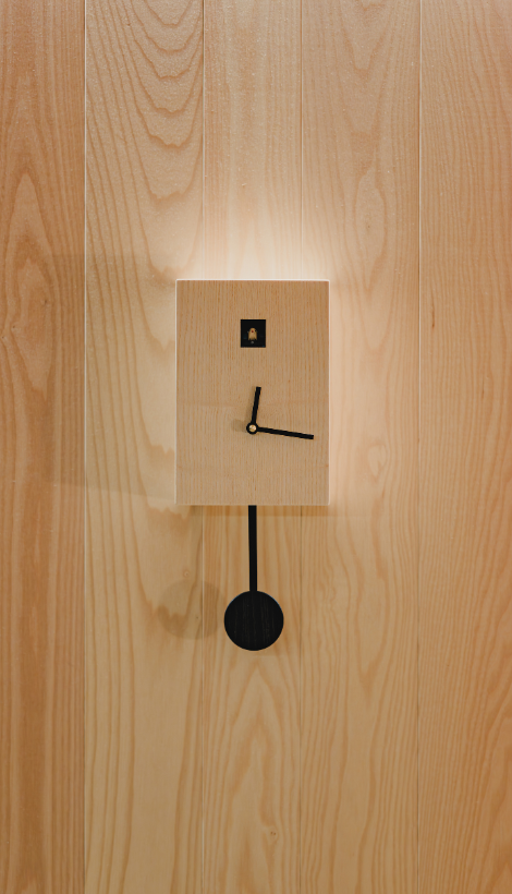 Horloge murale design minimaliste sur un mur en bois naturel, détail décoratif épuré illustrant l'art de vivre et le confort moderne au sein d'une suite itinérante SNUUG en Suisse.