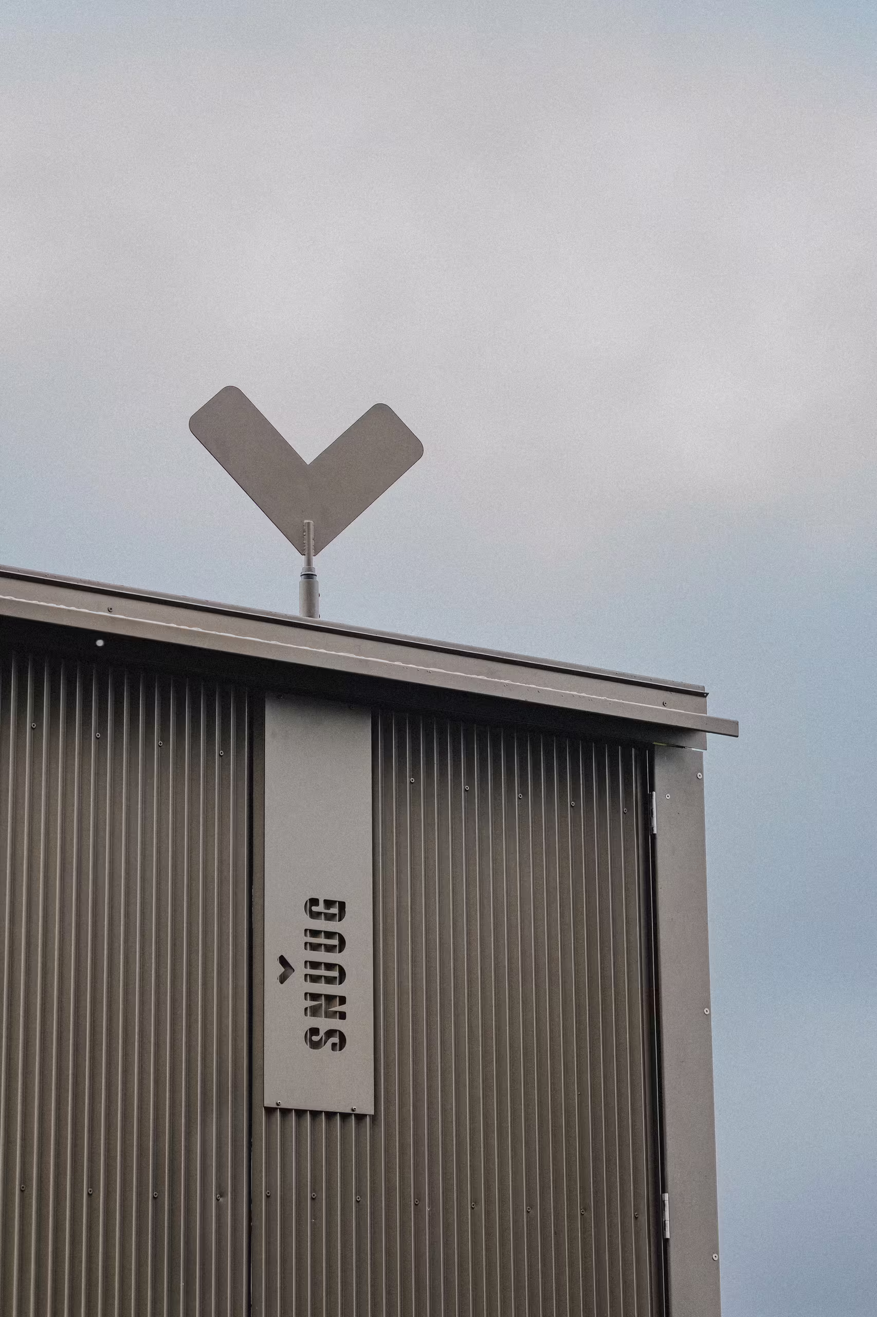 Logo de l'hôtel éco-responsable SNUUG sur la façade moderne et minimaliste d'une cabine haut de gamme en Suisse.