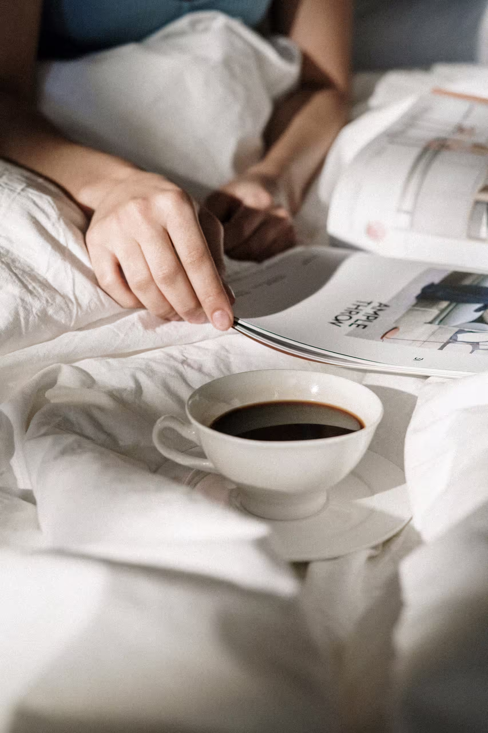 Moment de détente au lit avec une tasse de café chaud et un magazine, expérience de déconnexion absolue dans un hôtel de luxe SNUUG