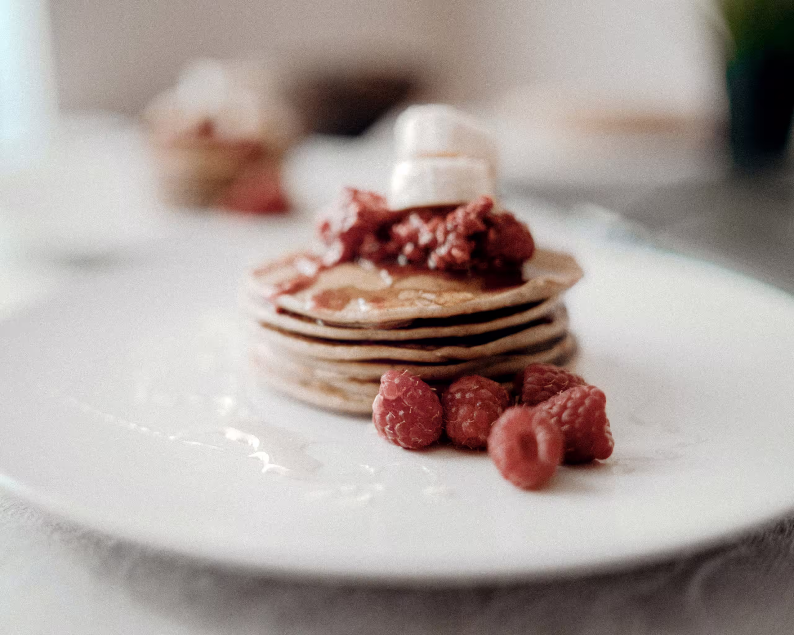 Pancakes faits maison avec framboises fraîches et banane, petit-déjeuner local et gourmand lors d'un séjour éco-touristique en Suisse.