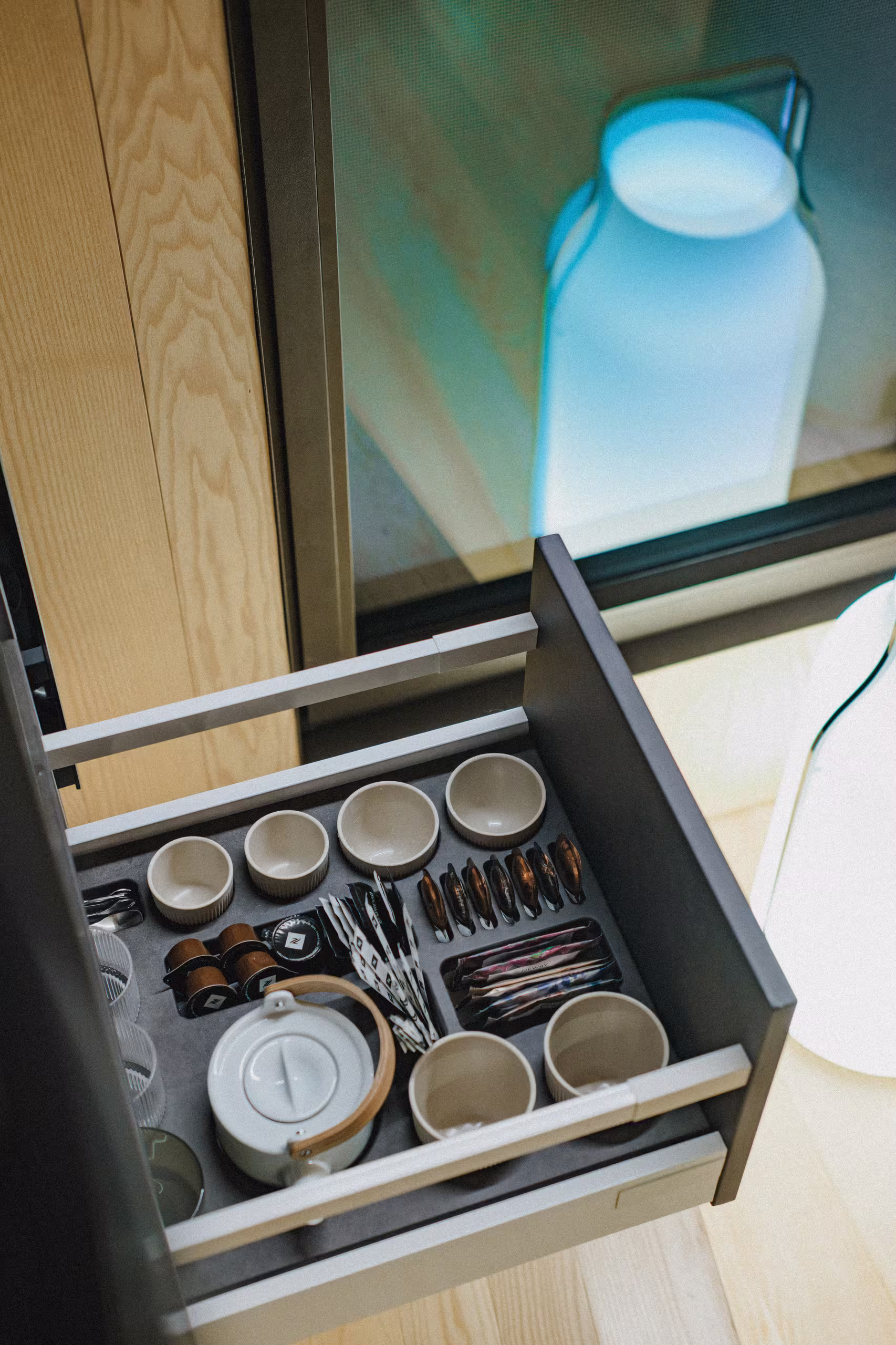 Tiroir aménagé avec théière, tasses et capsules de café dans une suite SNUUG, confort haut de gamme au cœur de votre retraite éphémère en Suisse.