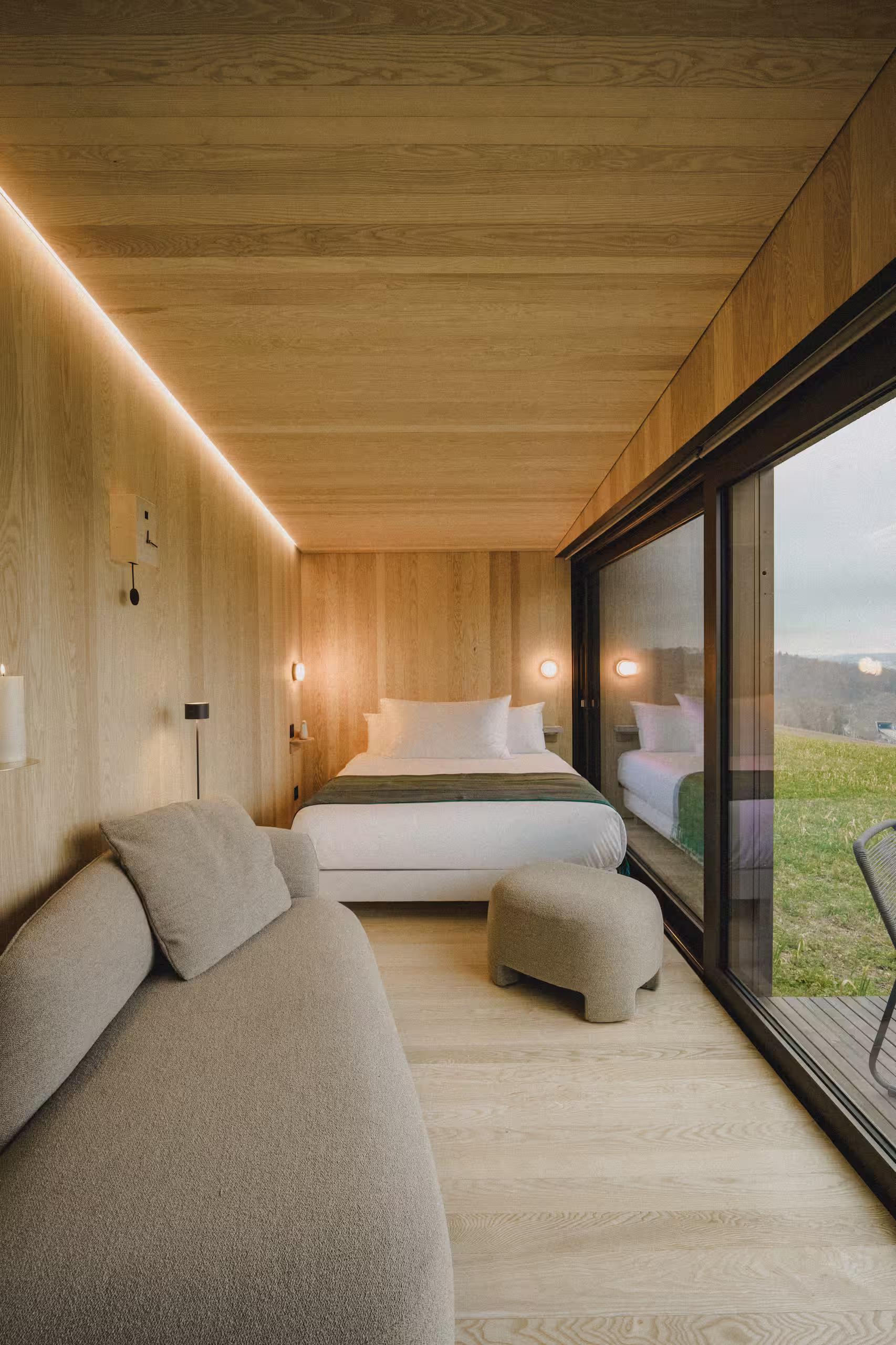 Intérieur élégant et éco-conçu d'une suite SNUUG avec grandes baies vitrées donnant sur les paysages suisses, alliance du confort 4 étoiles et de la durabilité.